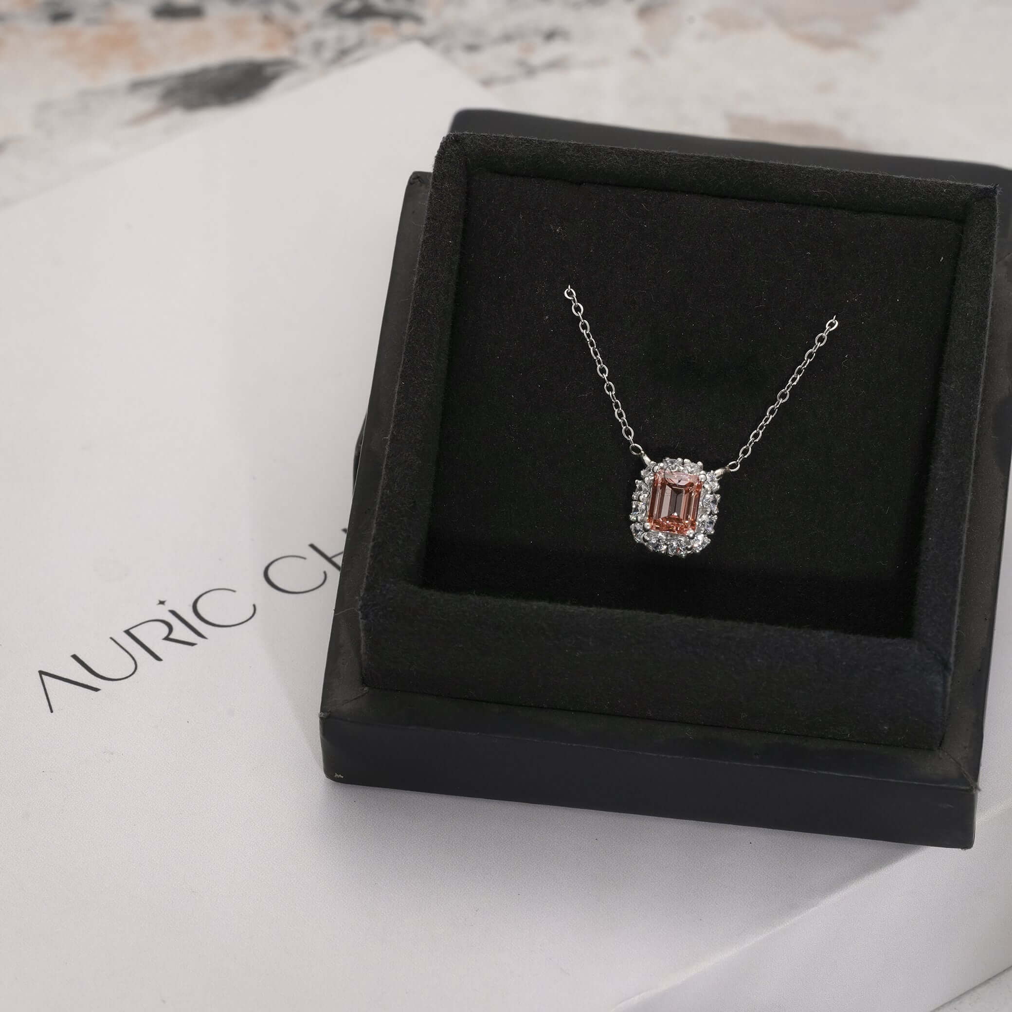 Fancy pink emerald cut lab grown diamond halo pendant necklace shown in elegant display, perfect for luxury gifting.