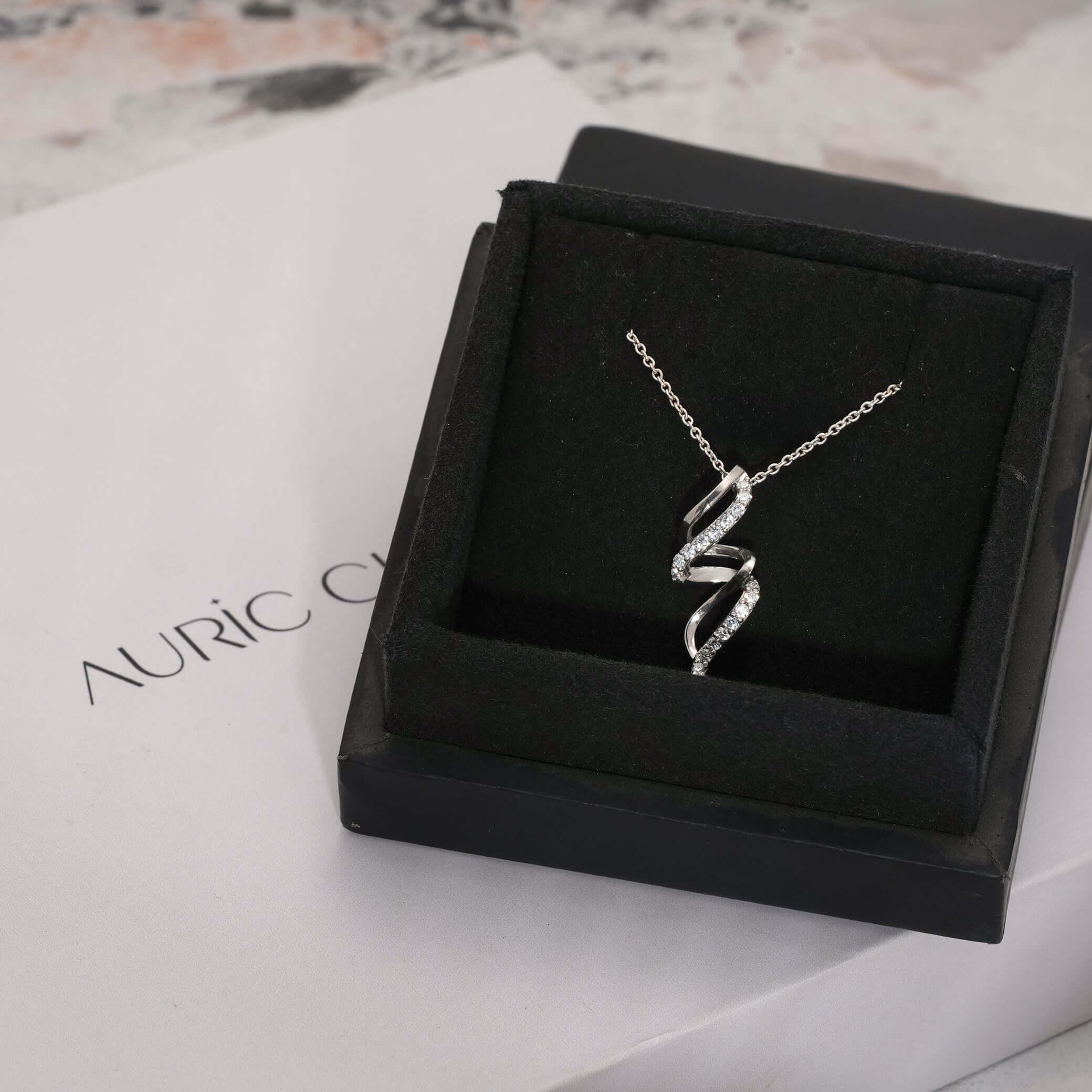 Curved spiral lab-grown diamond pendant necklace displayed in a luxury box, symbolizing elegance and sustainable jewelry.