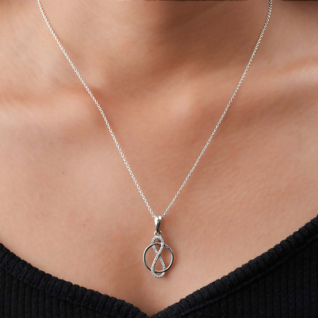 Sustainable jewelry featuring an infinity circle pendant with lab-grown diamonds, elegantly worn on neck, embodying timeless love.
