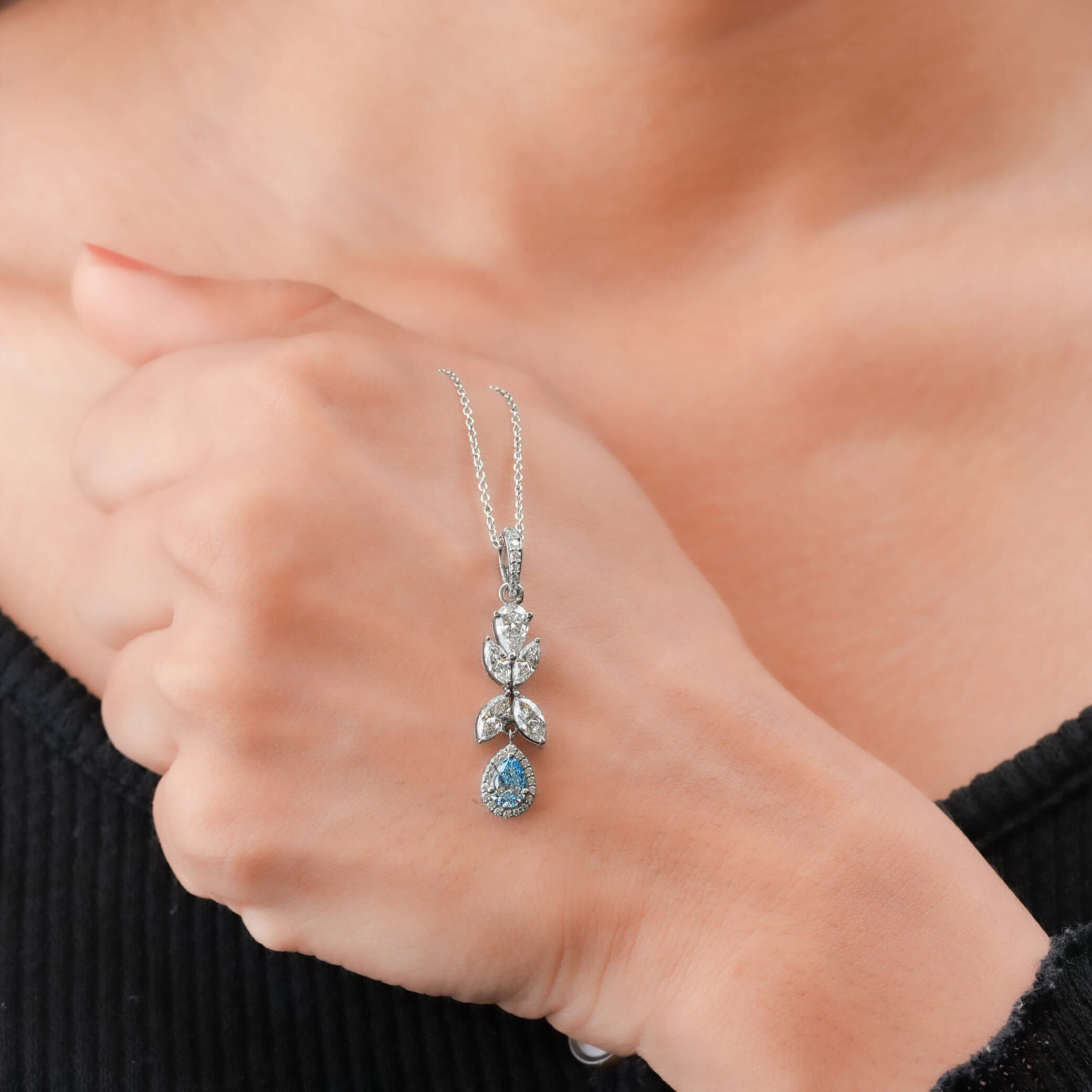 Profile view of diamond and blue sapphire pendant in white gold, highlighting intricate design and craftsmanship.