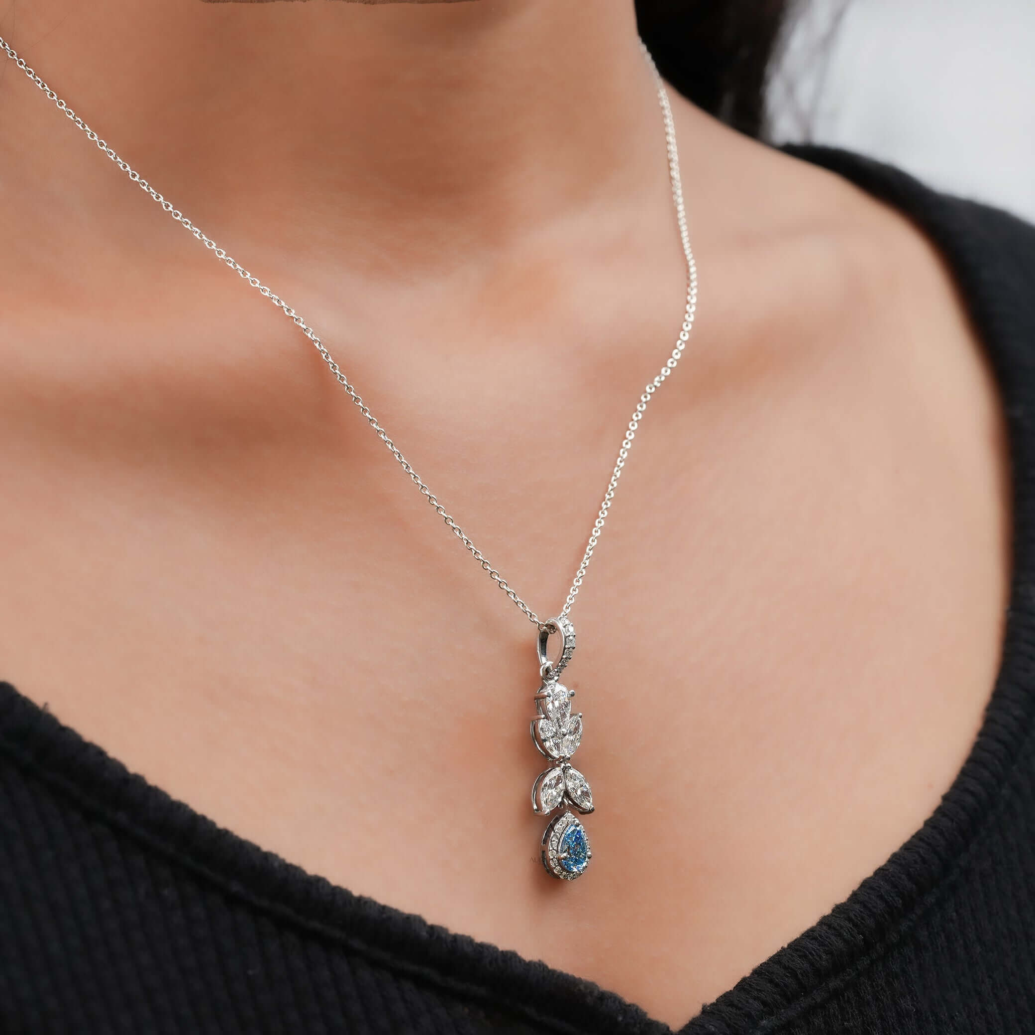 Side view of white gold pendant with marquise and pear-cut lab-grown diamonds and blue sapphire drop.