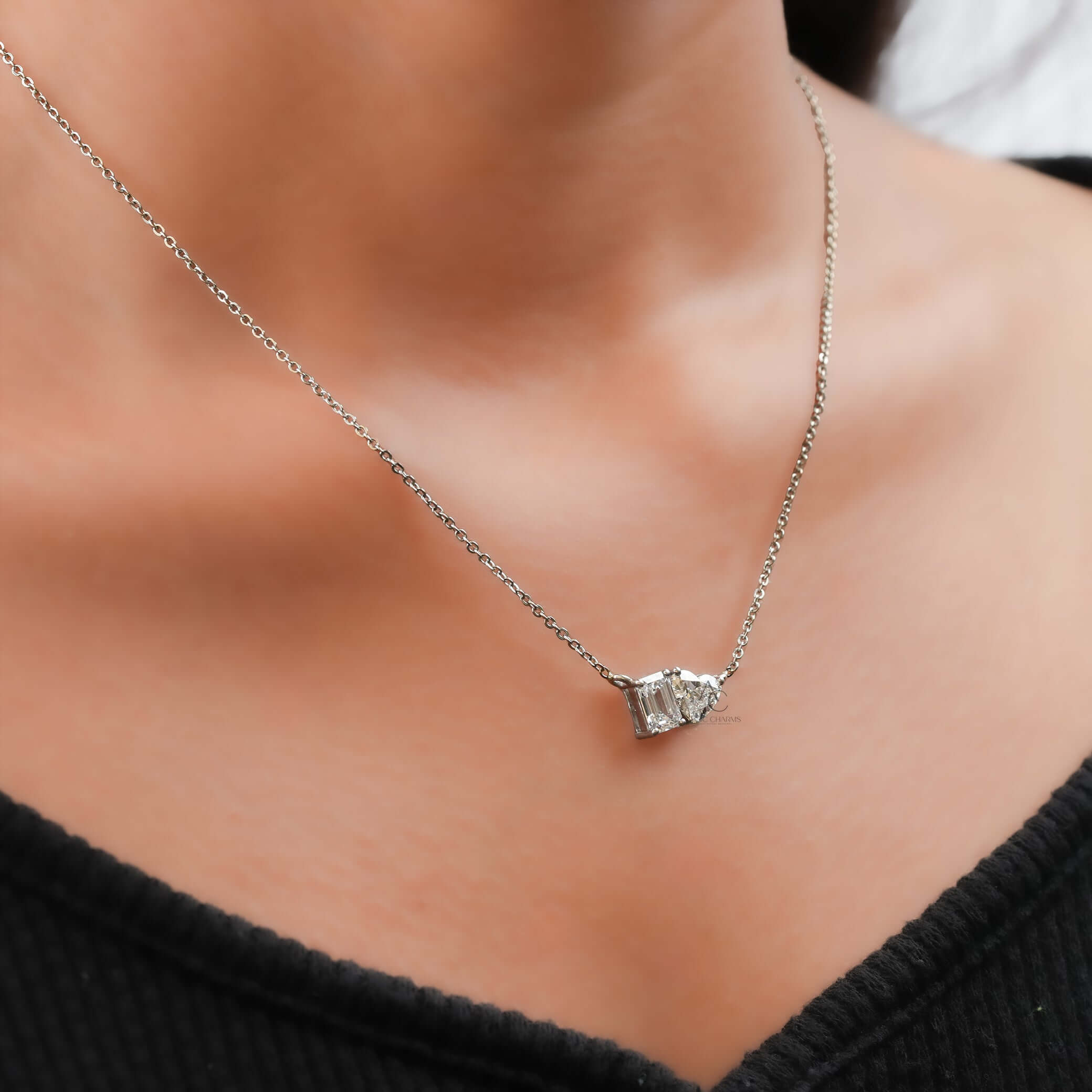 Model wearing a luxury Toi et Moi pendant featuring a stunning lab grown diamond with emerald and heart cuts, symbolizing love.