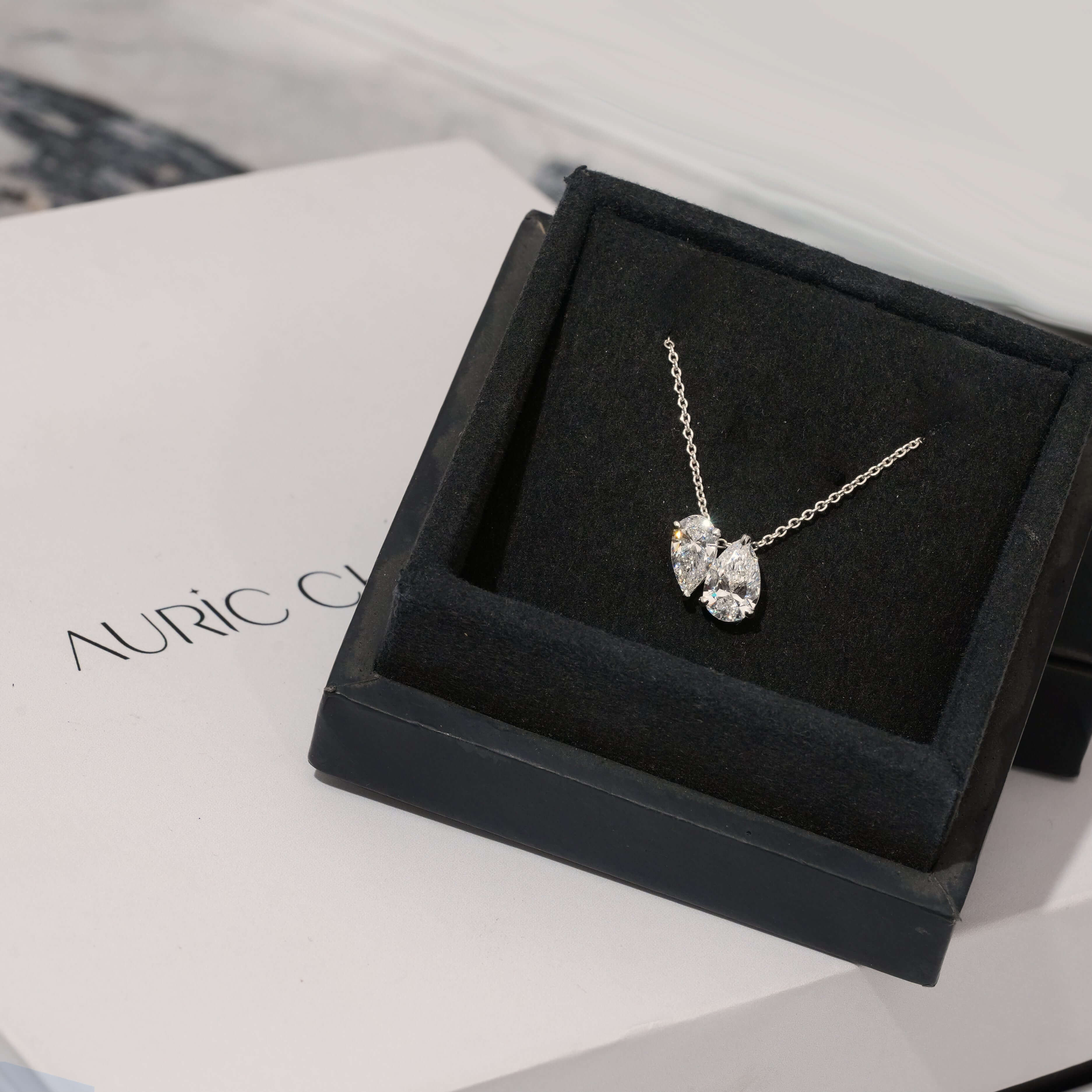 Toi et Moi Pear Cut Lab Grown Diamond Pendant Necklace displayed in a luxurious box, showcasing its elegant design on a classic chain.