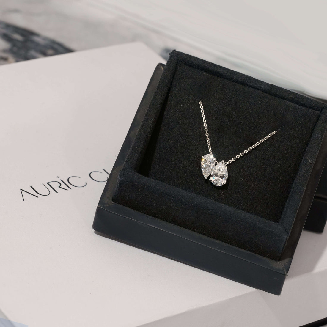 Toi et Moi Pear Cut Lab Grown Diamond Pendant Necklace displayed in a luxurious box, showcasing its elegant design on a classic chain.