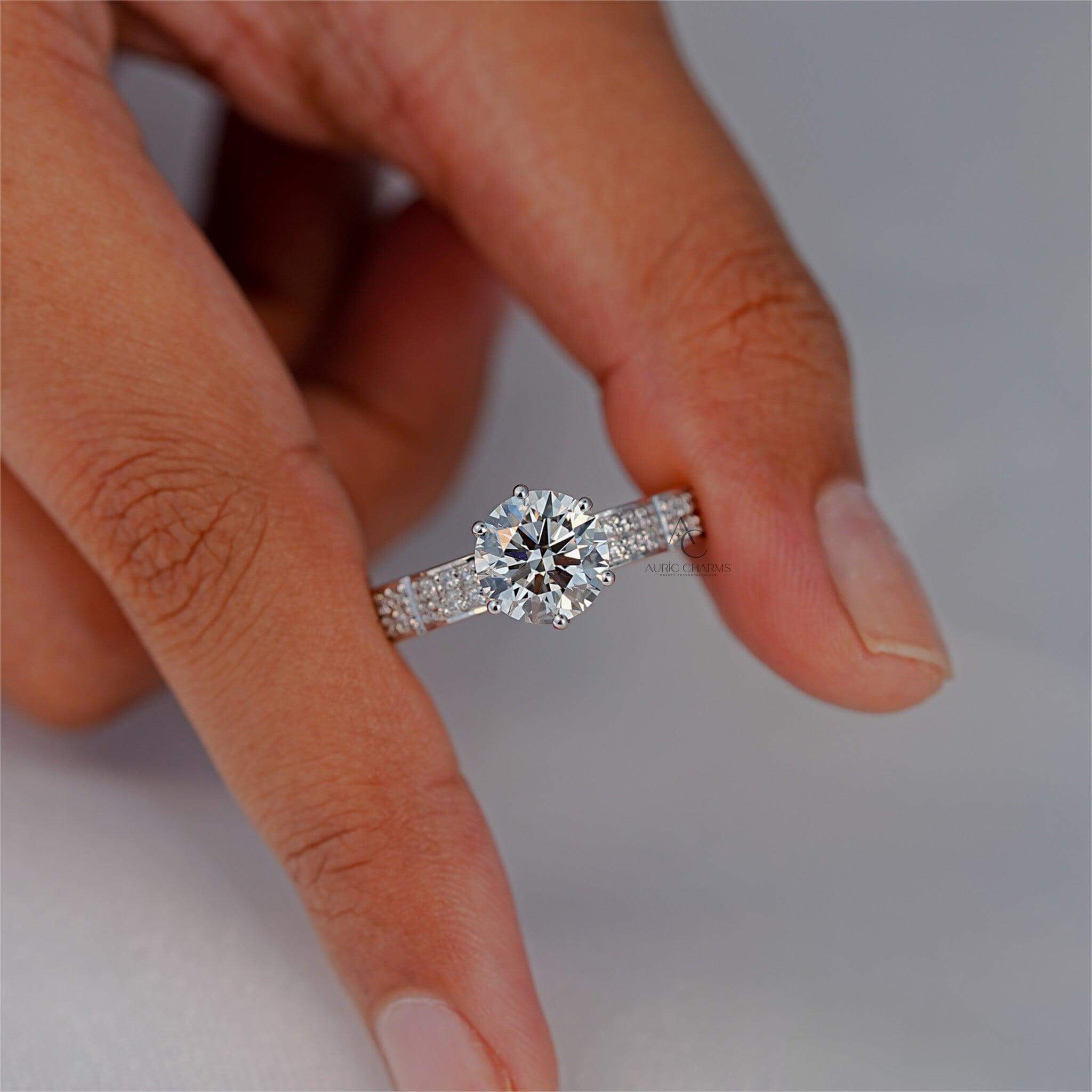 Diamond engagement ring showcased between fingertips.