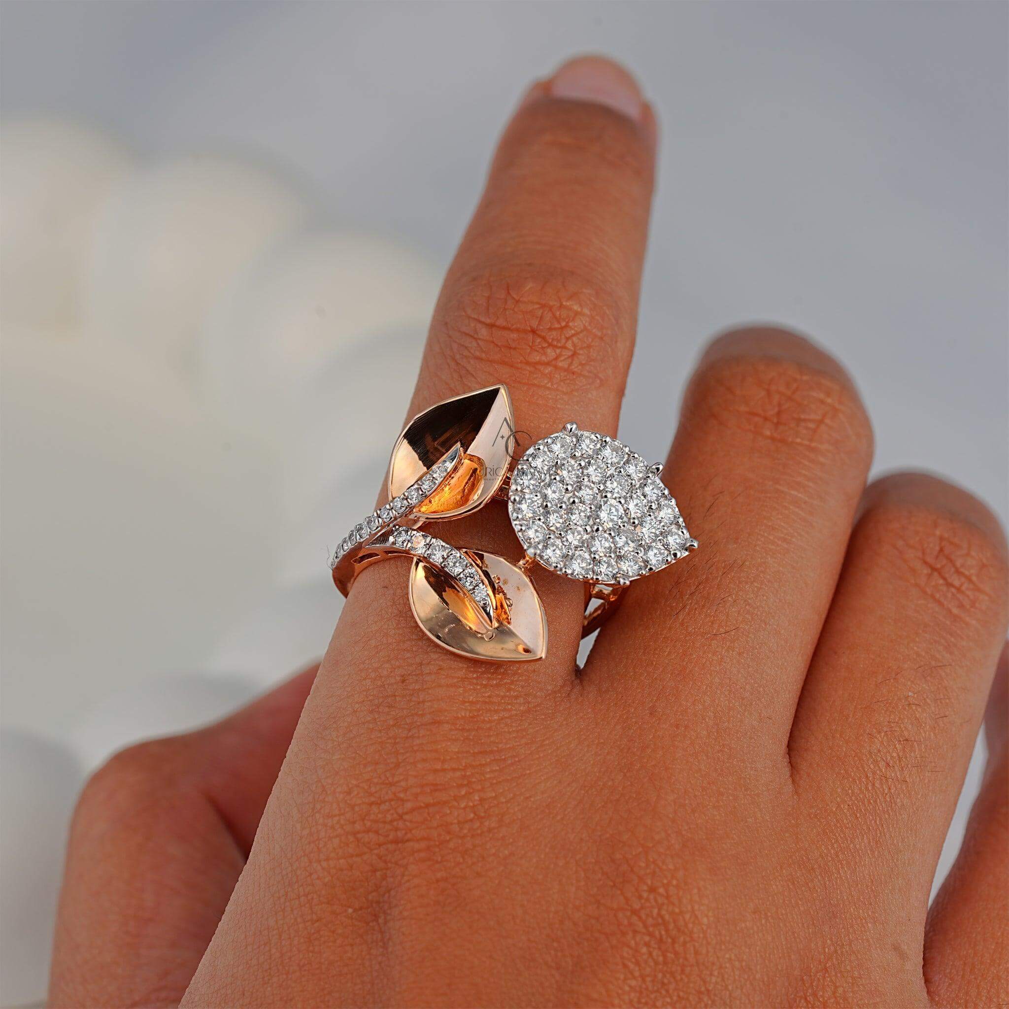 A nature-inspired dual-design ring featuring a pear-shaped diamond cluster paired with rose gold leaves, worn on a hand for an elegant look.
