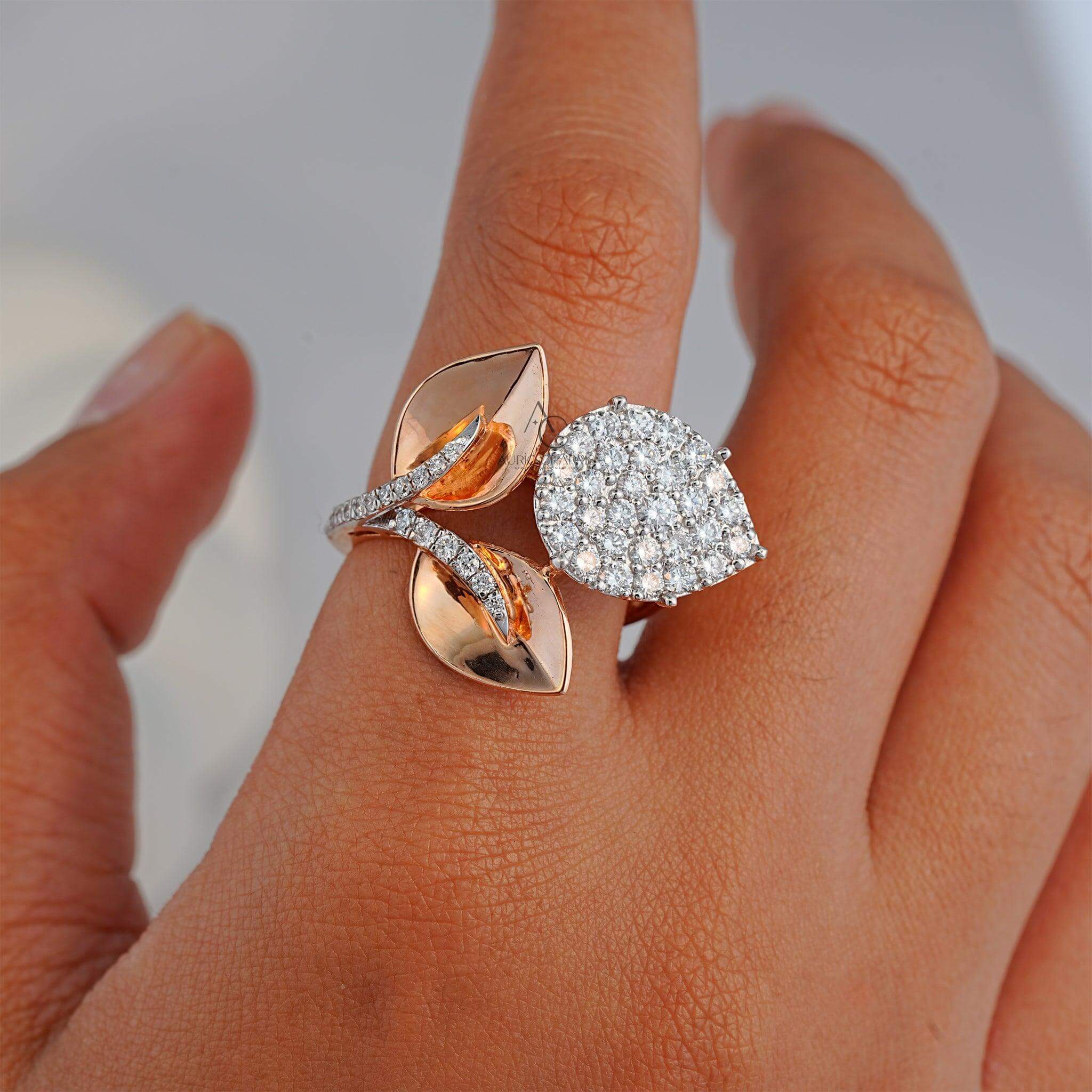 Close-up of a unique leaf-inspired ring, showcasing a pear-shaped diamond cluster on one side and sleek rose gold leaves on the other, accentuated by sparkling diamonds along the stem.