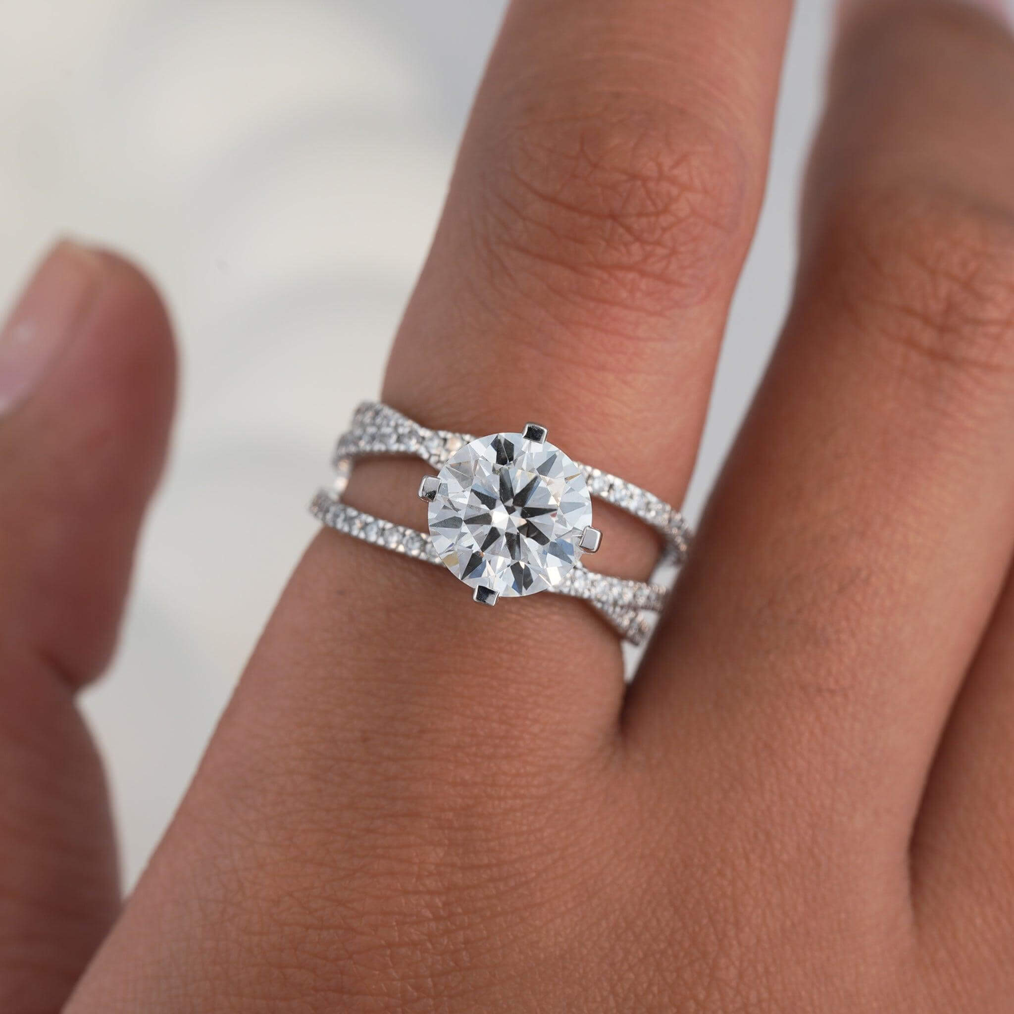 Hand model showcasing a stunning diamond engagement ring with split-shank pave band in white gold.
