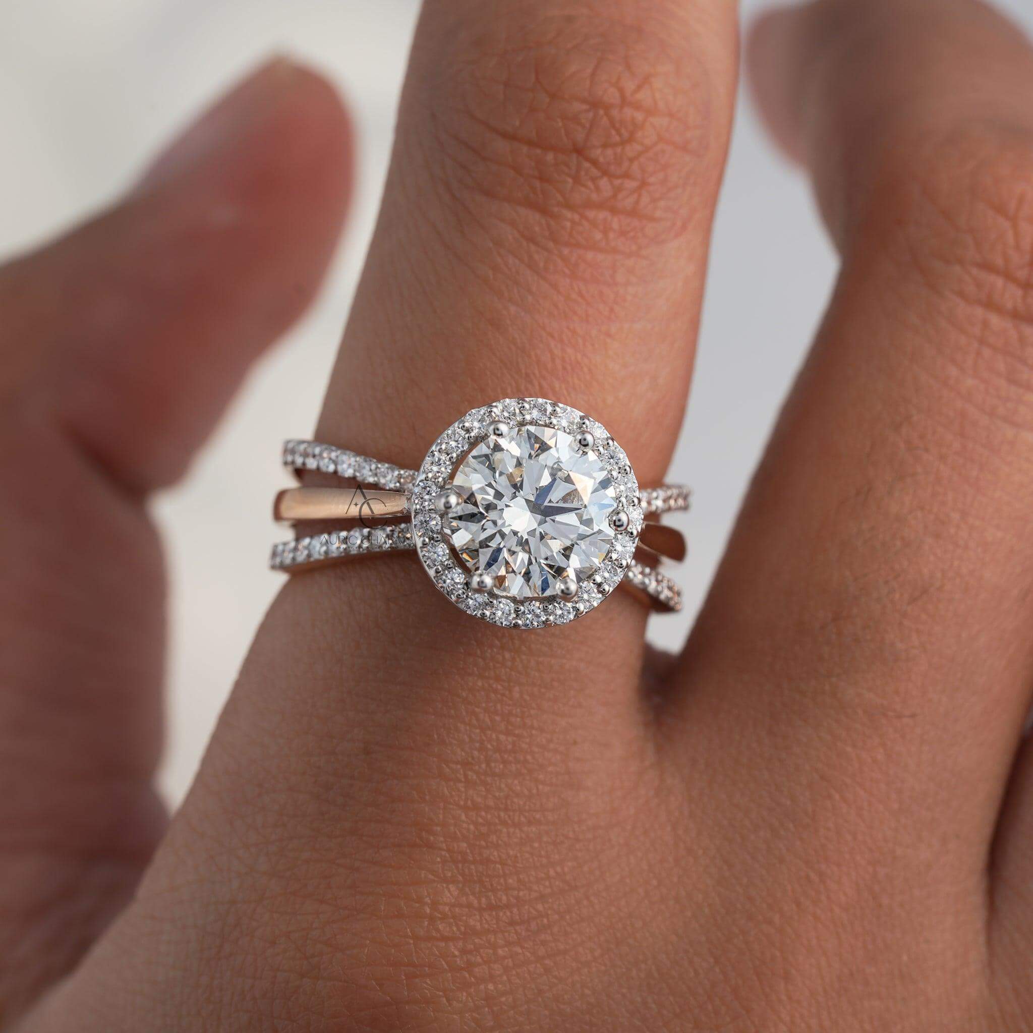 Round halo diamond engagement ring with rose gold band on finger, sparkling brilliance.