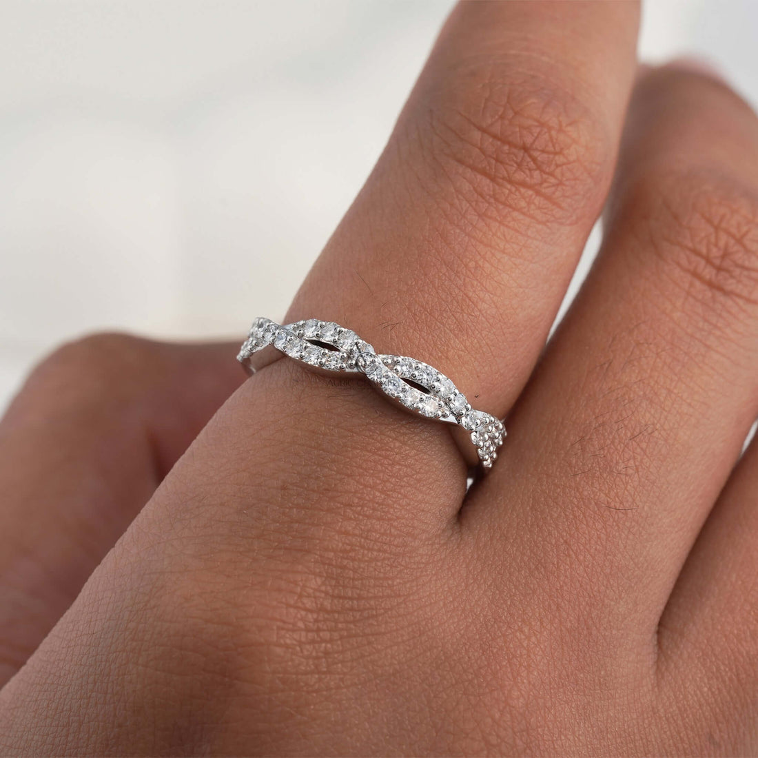 Diamond ring with a twisted band on finger.