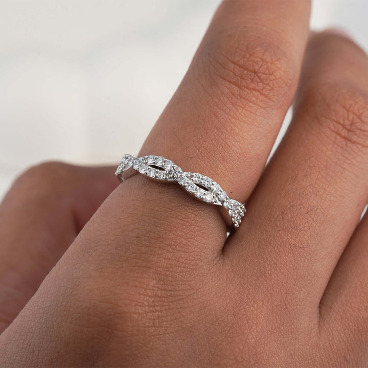 Diamond ring with a twisted band on finger.