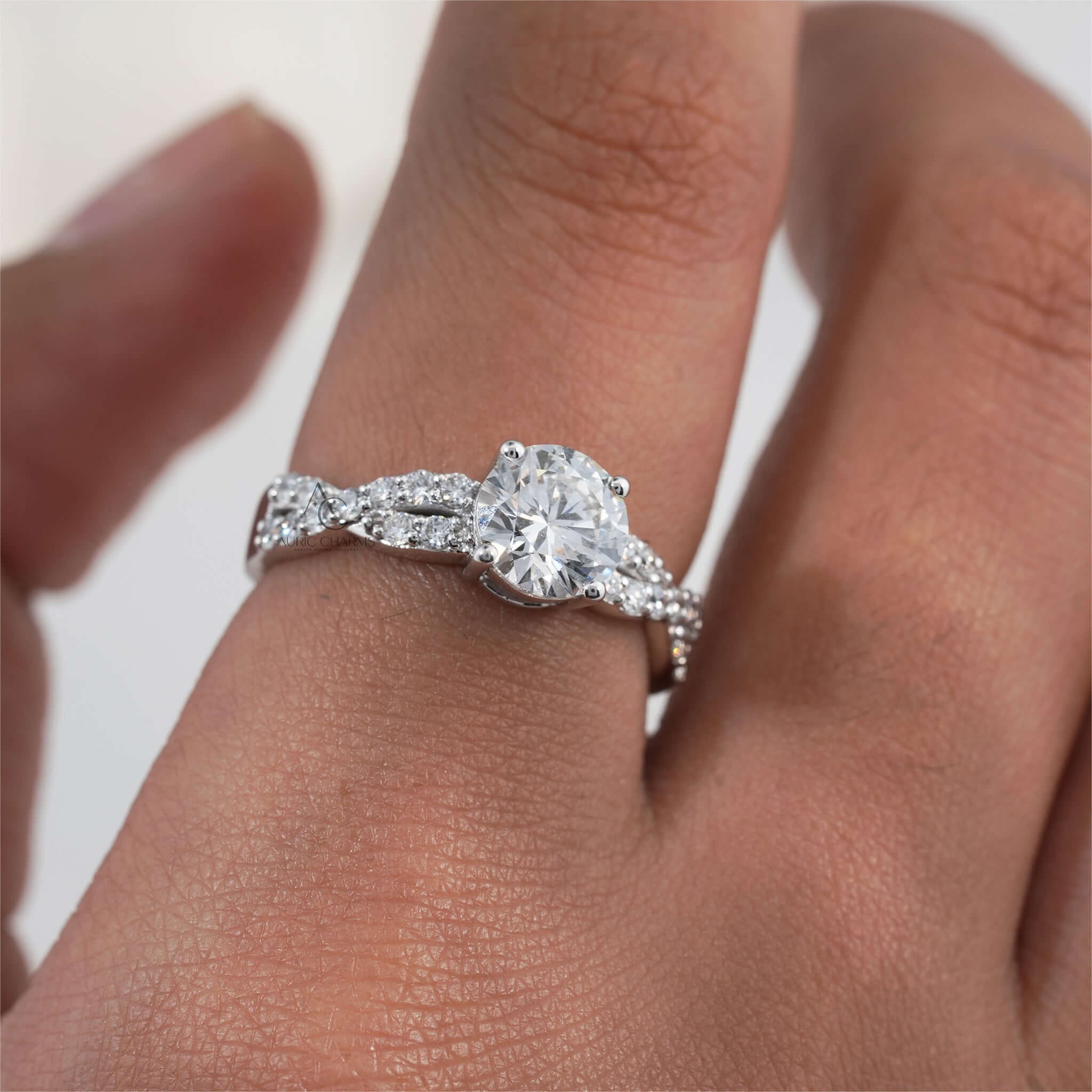 Round-cut diamond engagement ring with side stones, worn on hand.