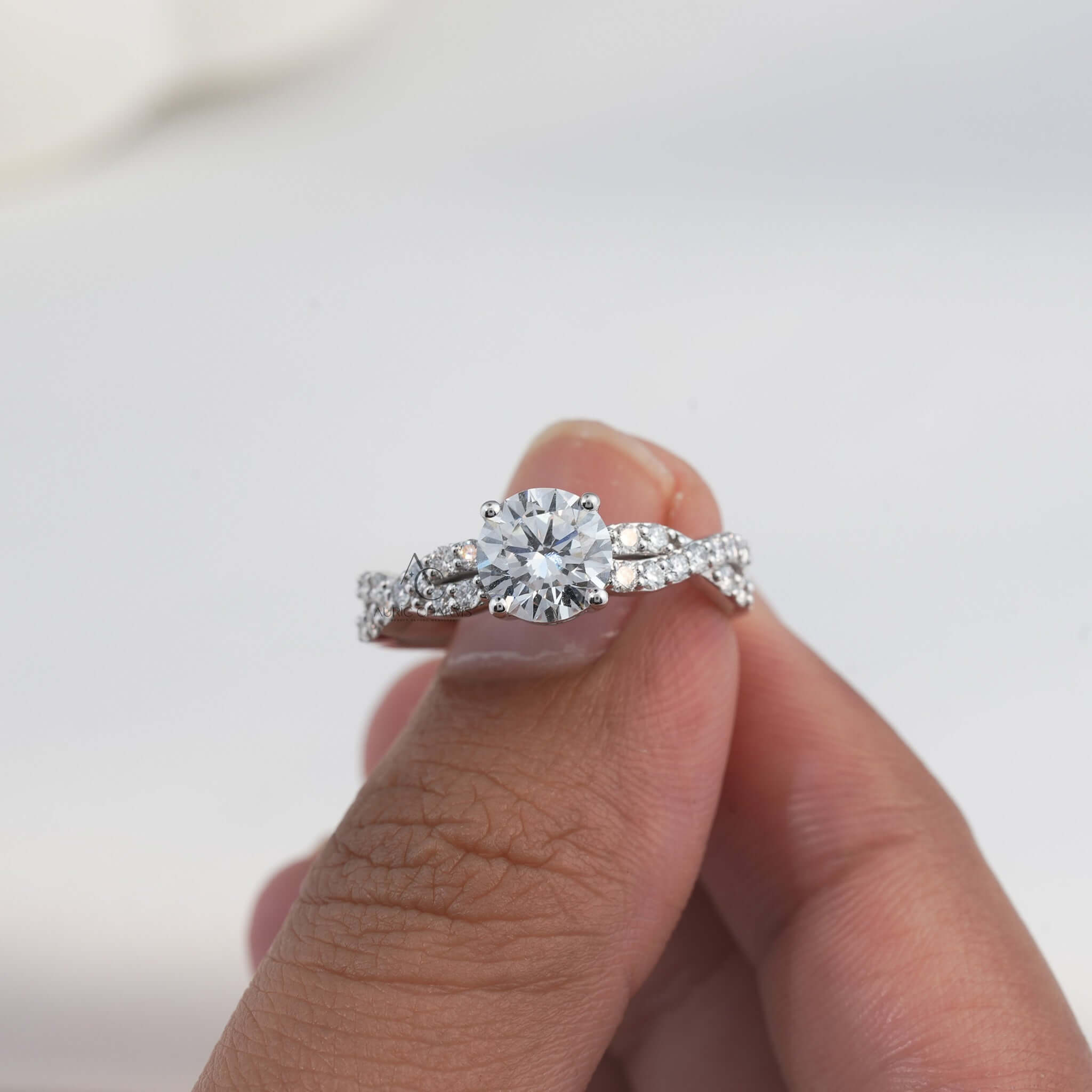 Close-up of diamond engagement ring with side stones, held by hand.