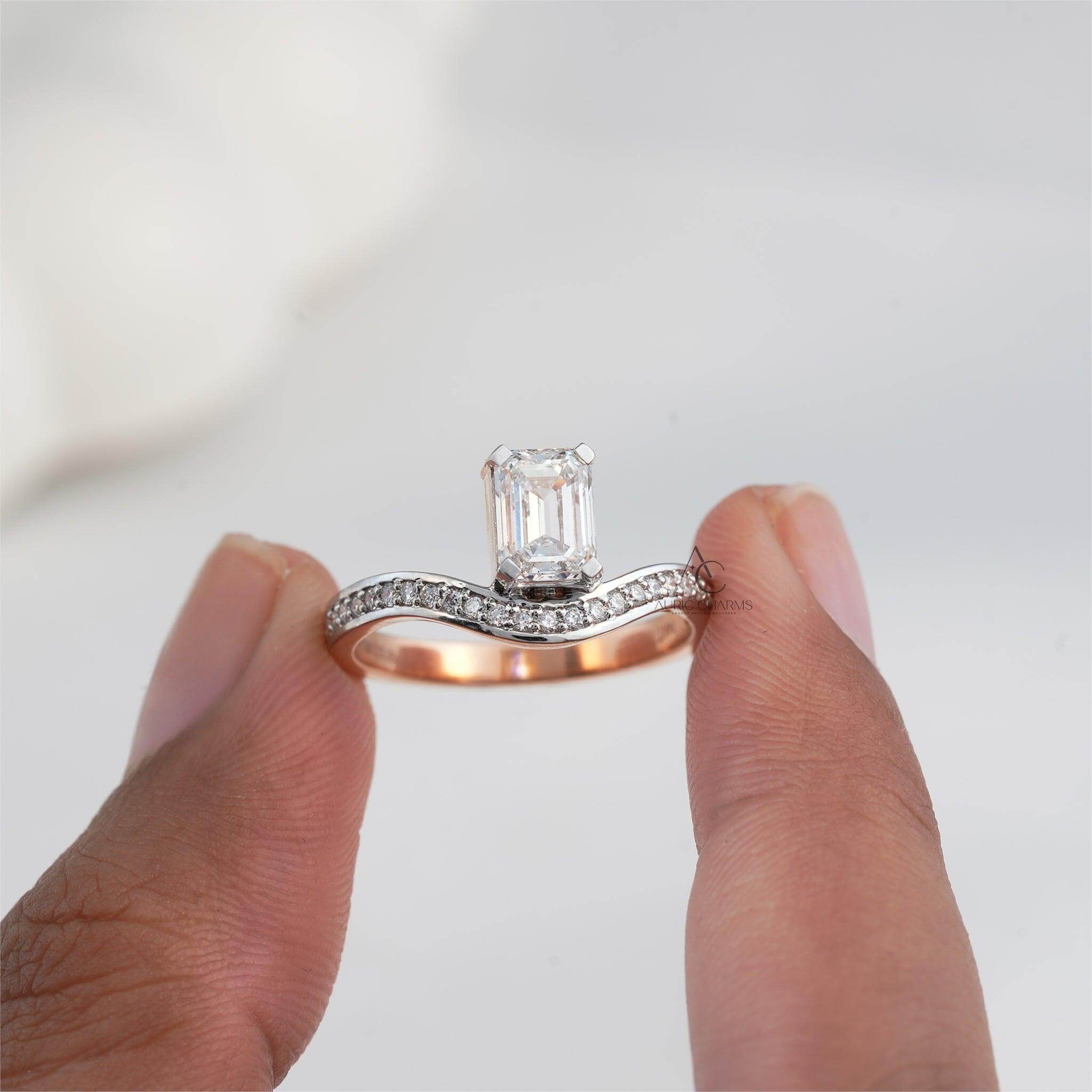 Emerald-cut diamond ring held between fingers showing its rose gold and diamond band.