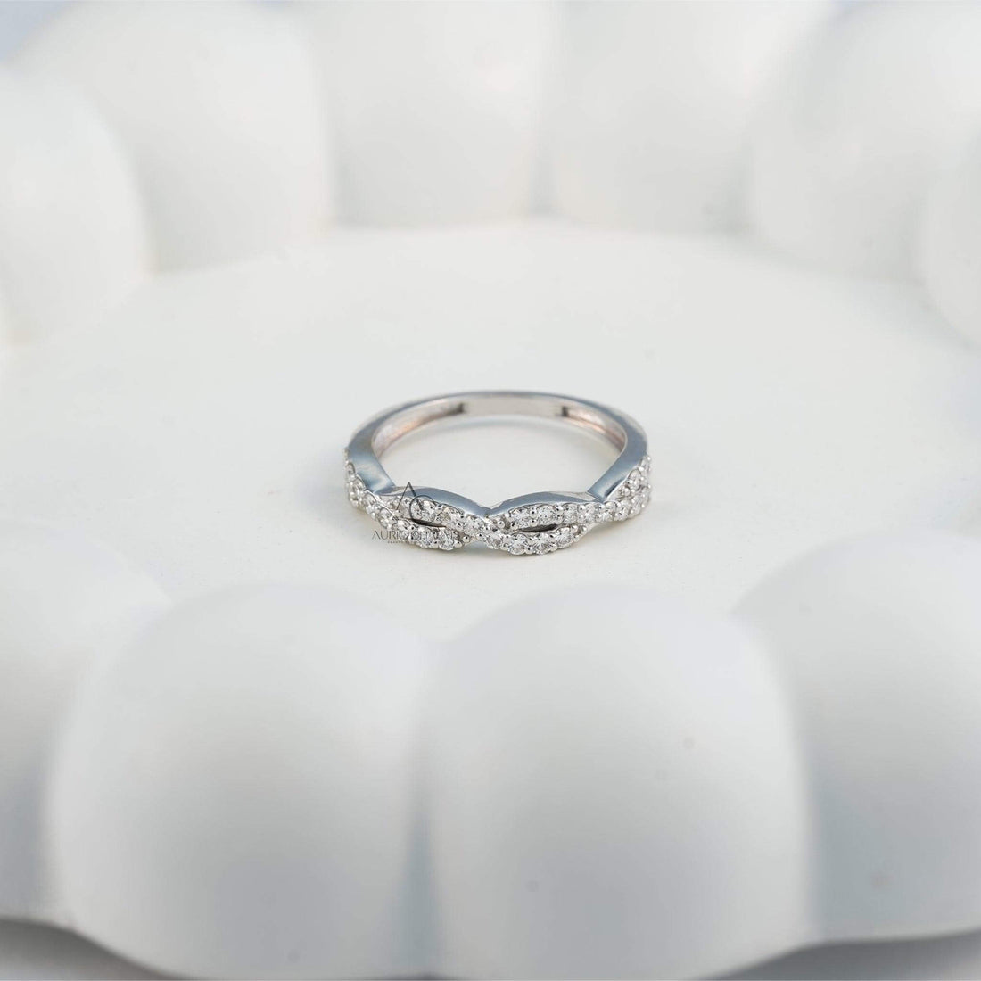 Close-up of a diamond-studded twisted wedding band on a hand.