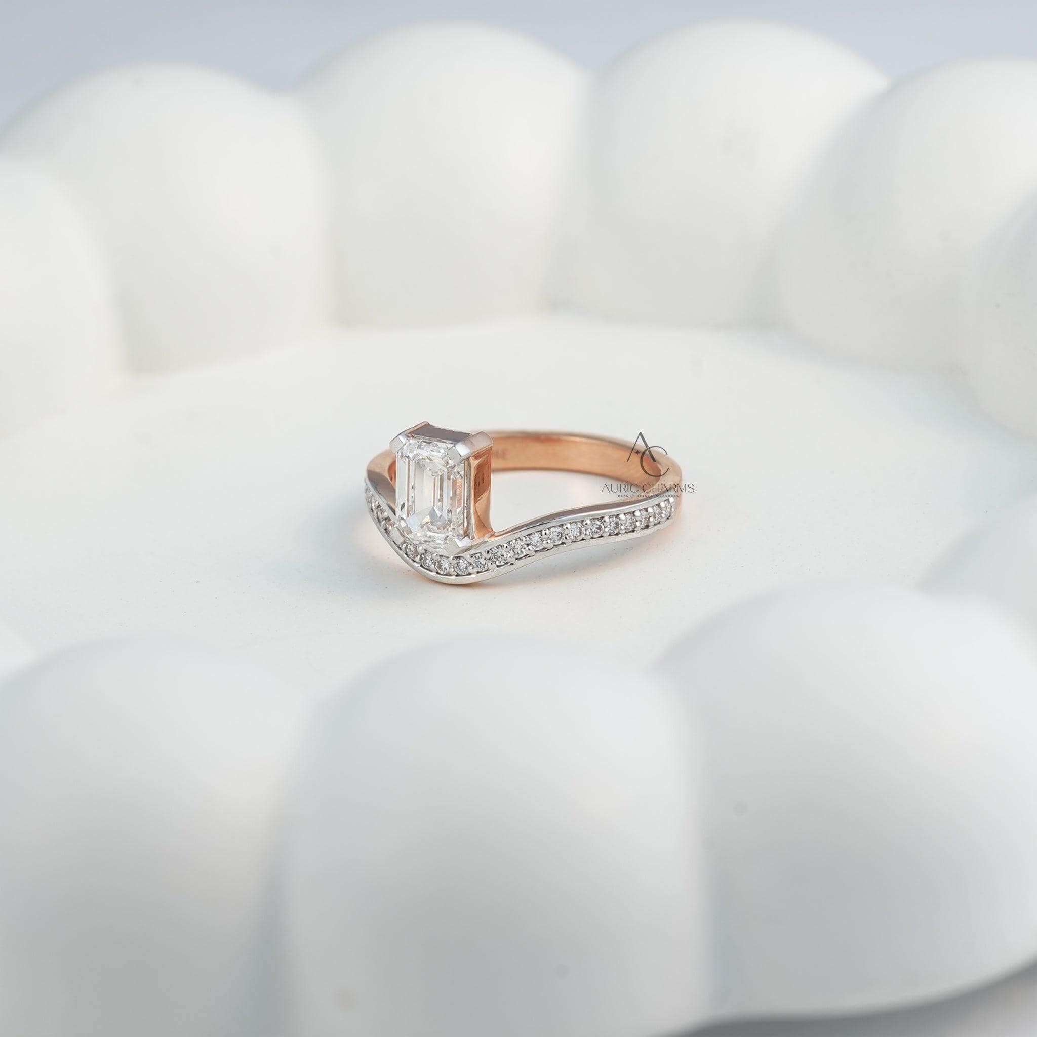 Side view of an emerald-cut diamond ring on a rose gold band with diamonds.