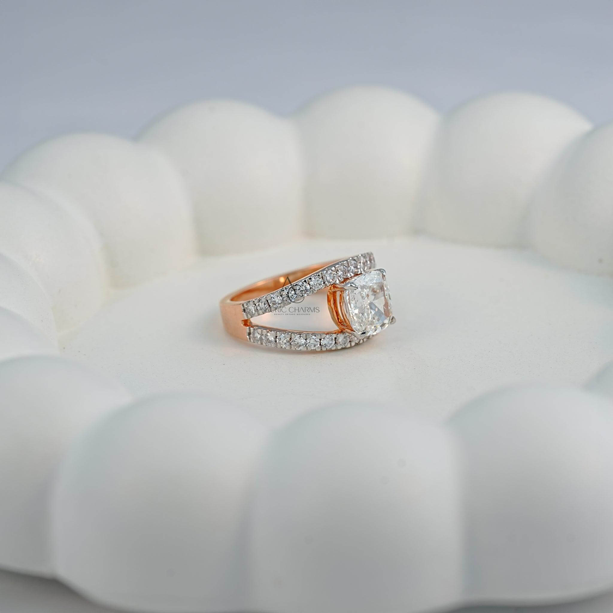 A rose-gold lab-grown diamond ring, featuring a split shank design, placed on a scalloped white dish.