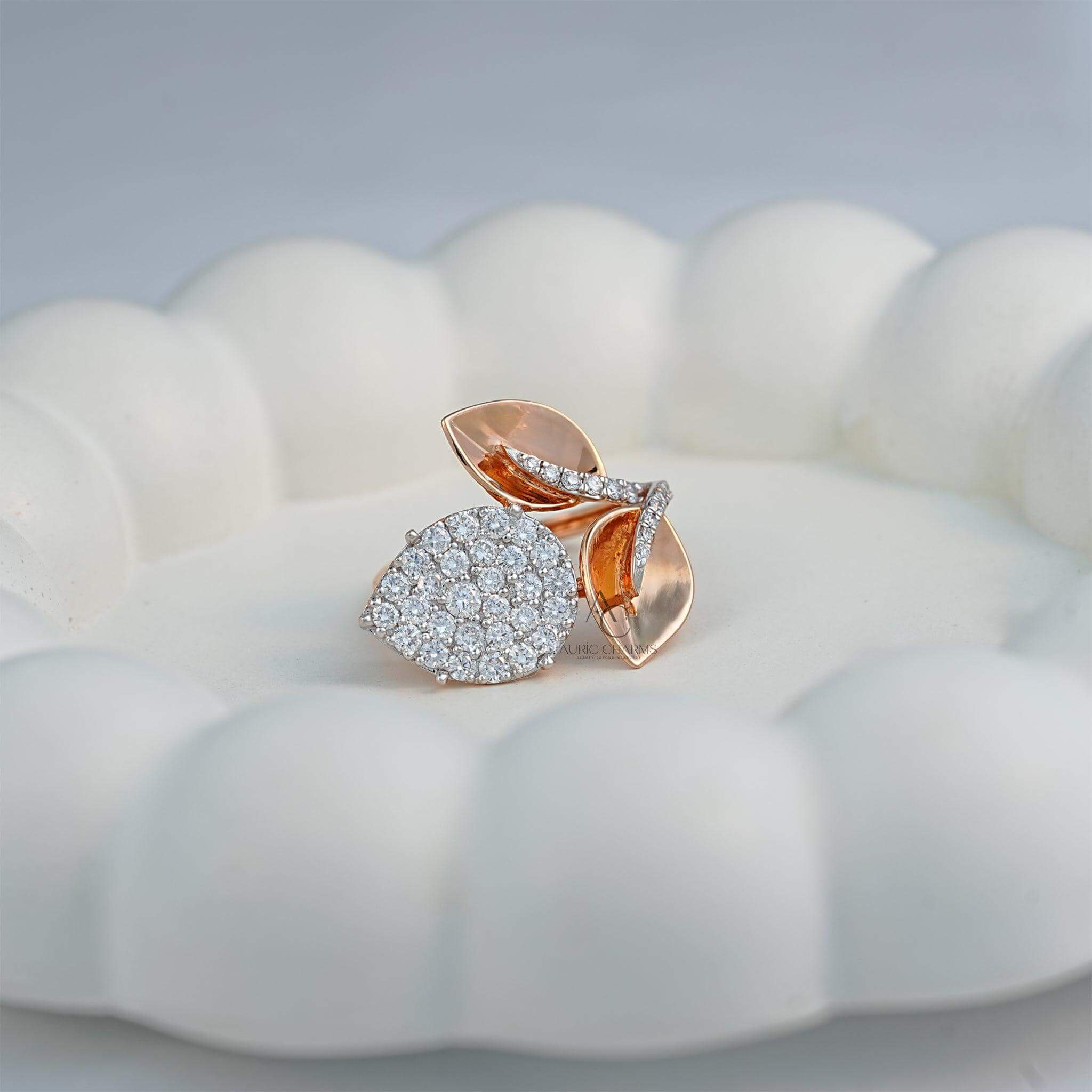 Side profile of a rose gold ring featuring a pear-shaped diamond cluster and two diamond-accented leaves, elegantly resting on a decorative surface.