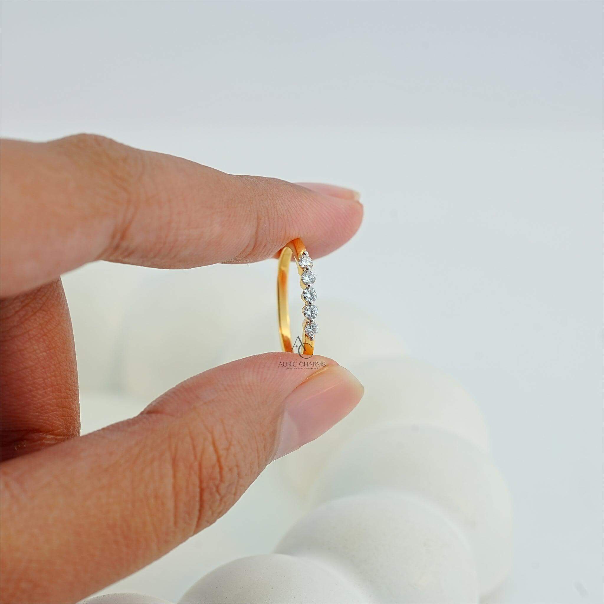 Hand holding a delicate diamond-studded gold ring, highlighting premium craftsmanship.