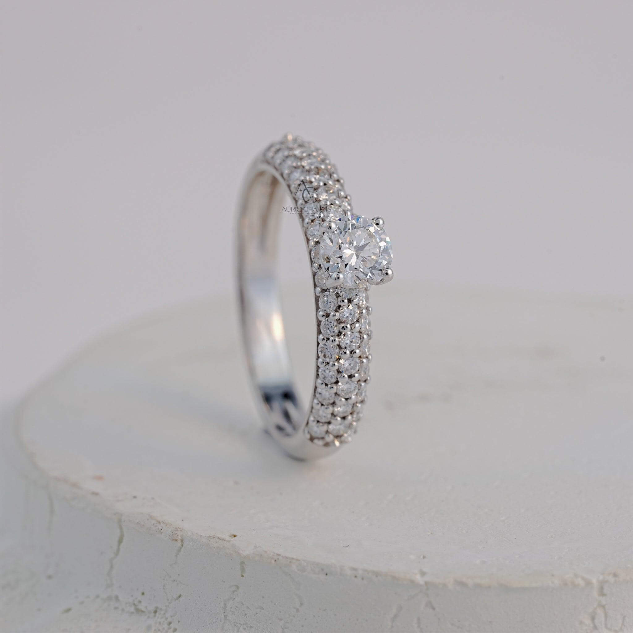 A three-dimensional angle of a platinum diamond ring showcasing the round-cut diamond and its triple pavé band for a glamorous appearance.