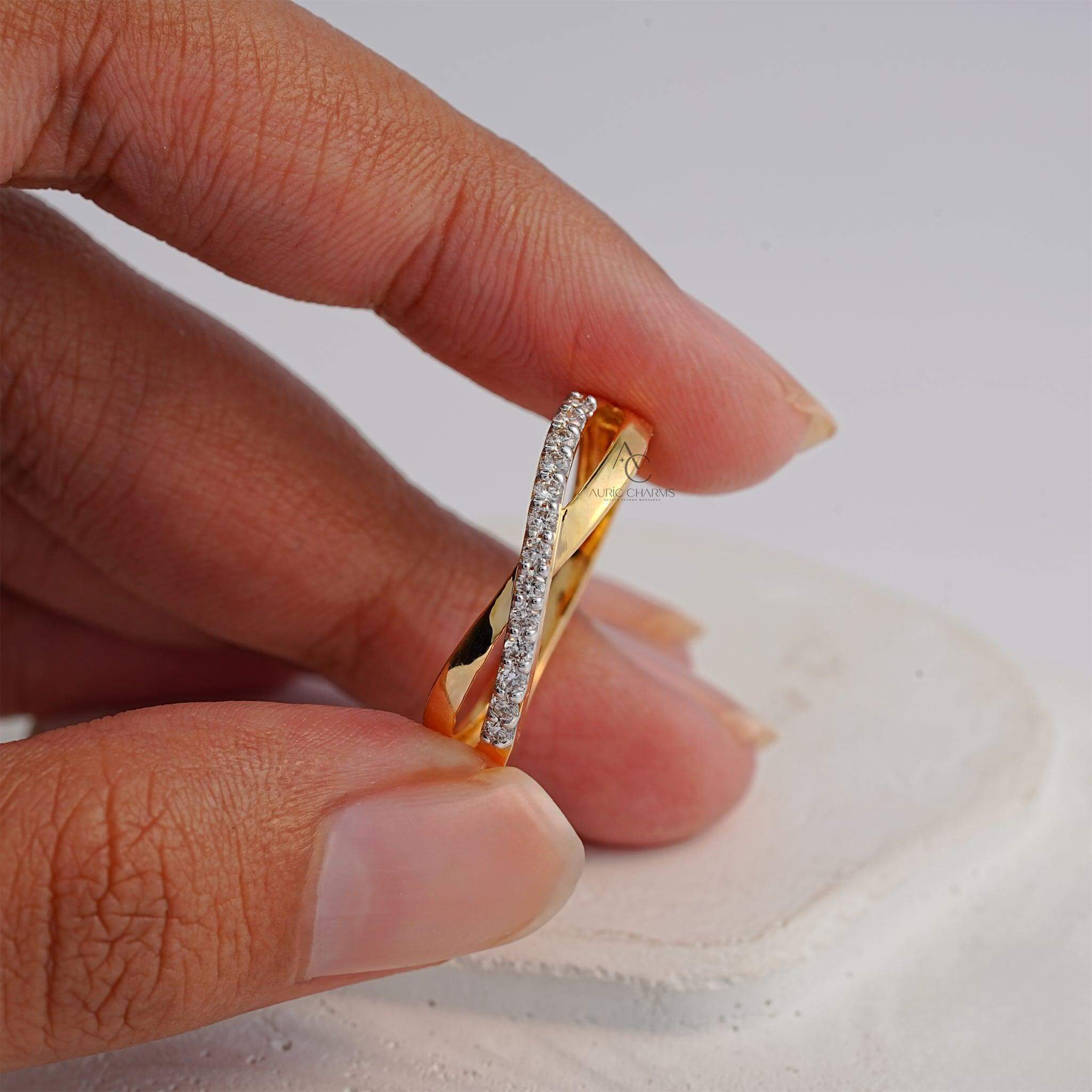 Gold diamond ring held between fingers, emphasizing its intricate design.