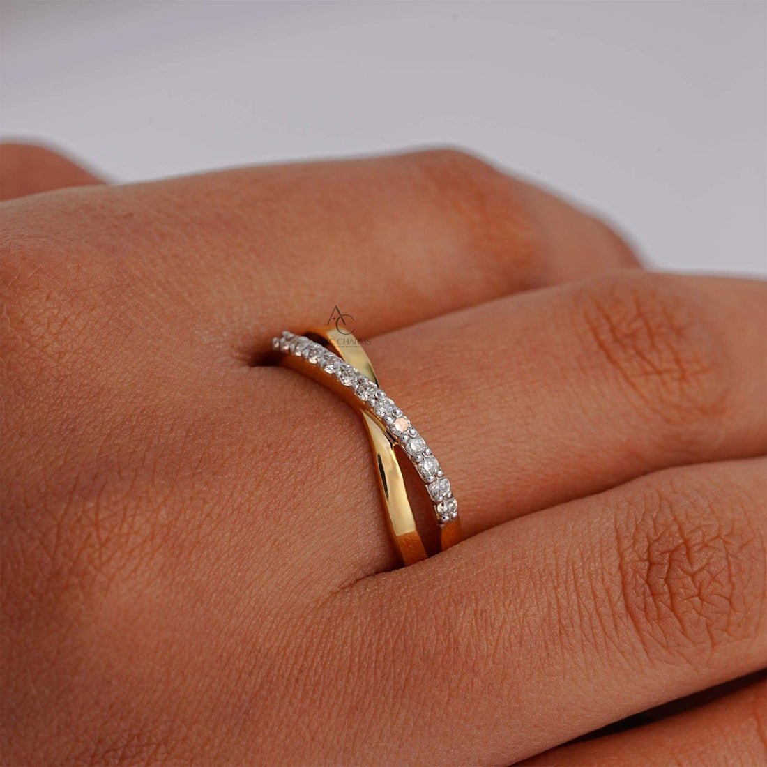 Crisscross gold diamond ring worn on a hand, showcasing its timeless beauty.