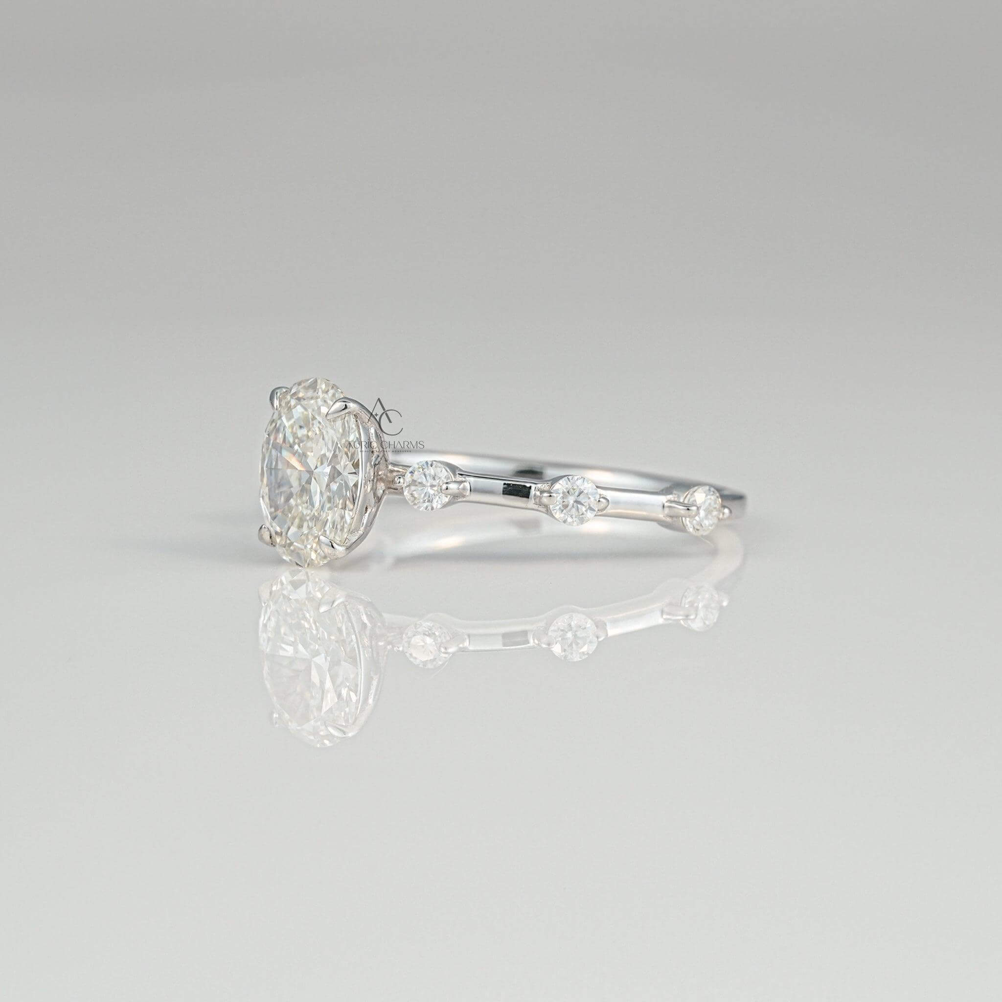 Side perspective of an oval-shaped diamond ring, showcasing a prong setting and a diamond-adorned thin band with intricate detailing.