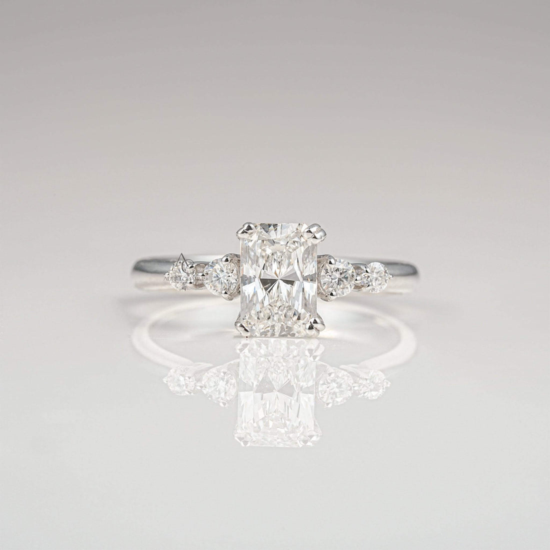 Radiant-cut diamond engagement ring with side stones on a sleek white gold band.