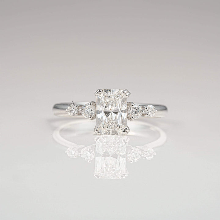 Radiant-cut diamond engagement ring with side stones on a sleek white gold band.