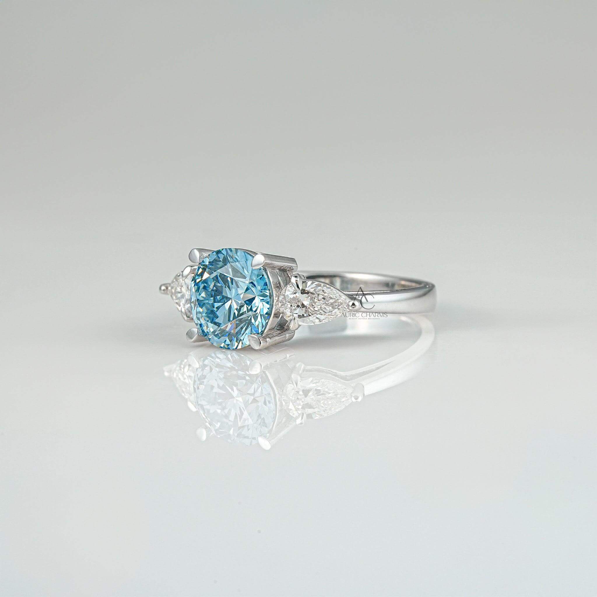 Side profile of a three-stone ring with a round blue diamond and shimmering pear-shaped side diamonds.
