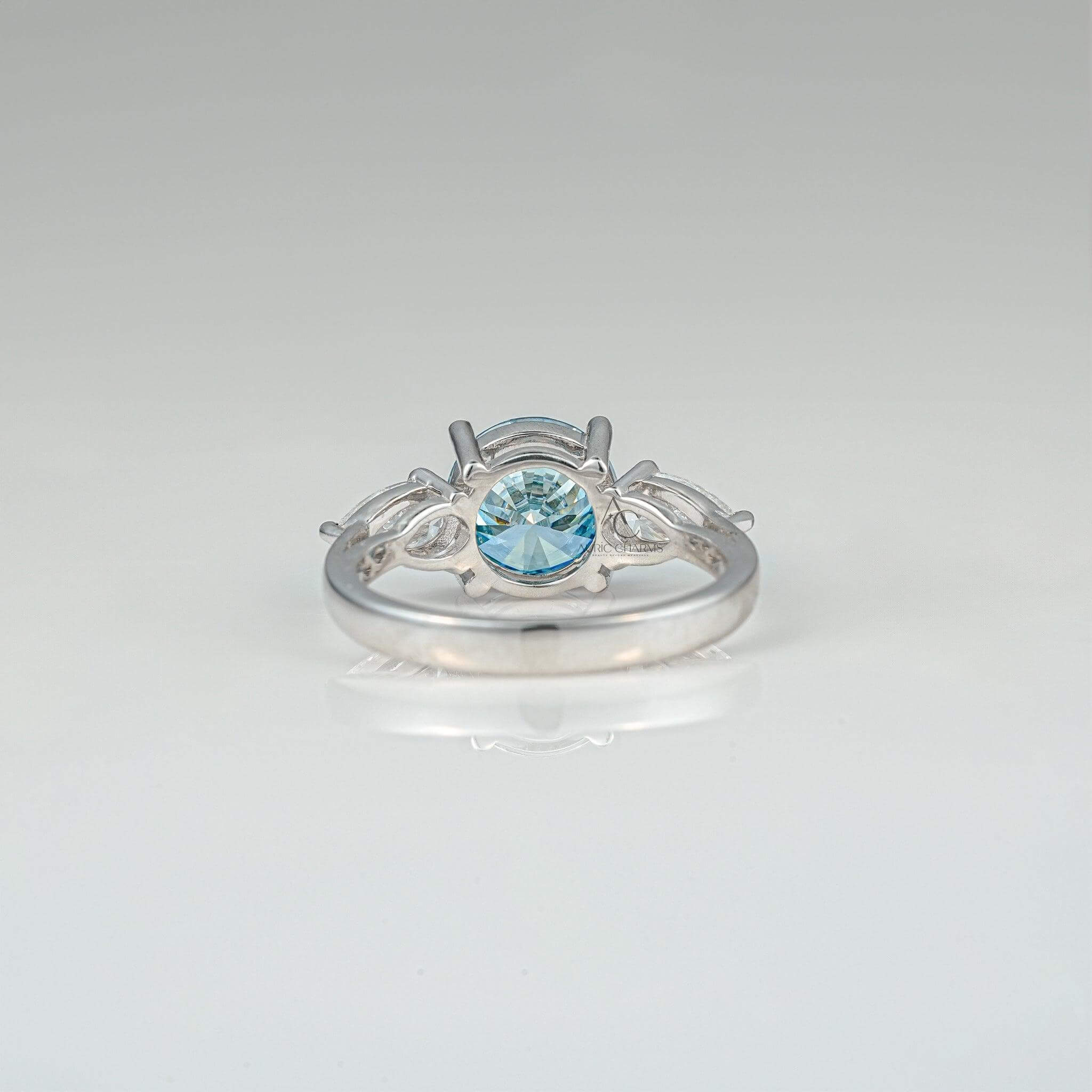 Back view of a blue diamond three-stone ring, showcasing intricate detailing and pear-shaped accents.