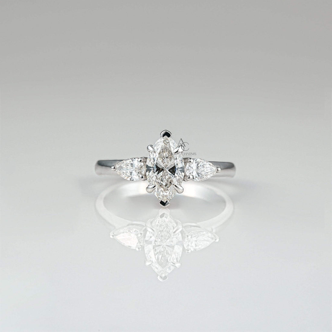 Marquise-cut diamond ring with pear accents on reflective surface, elegant solitaire design.