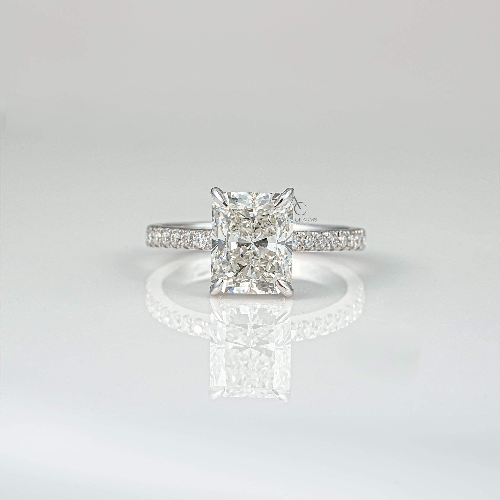 Radiant-cut diamond ring with a sleek band on a reflective surface.