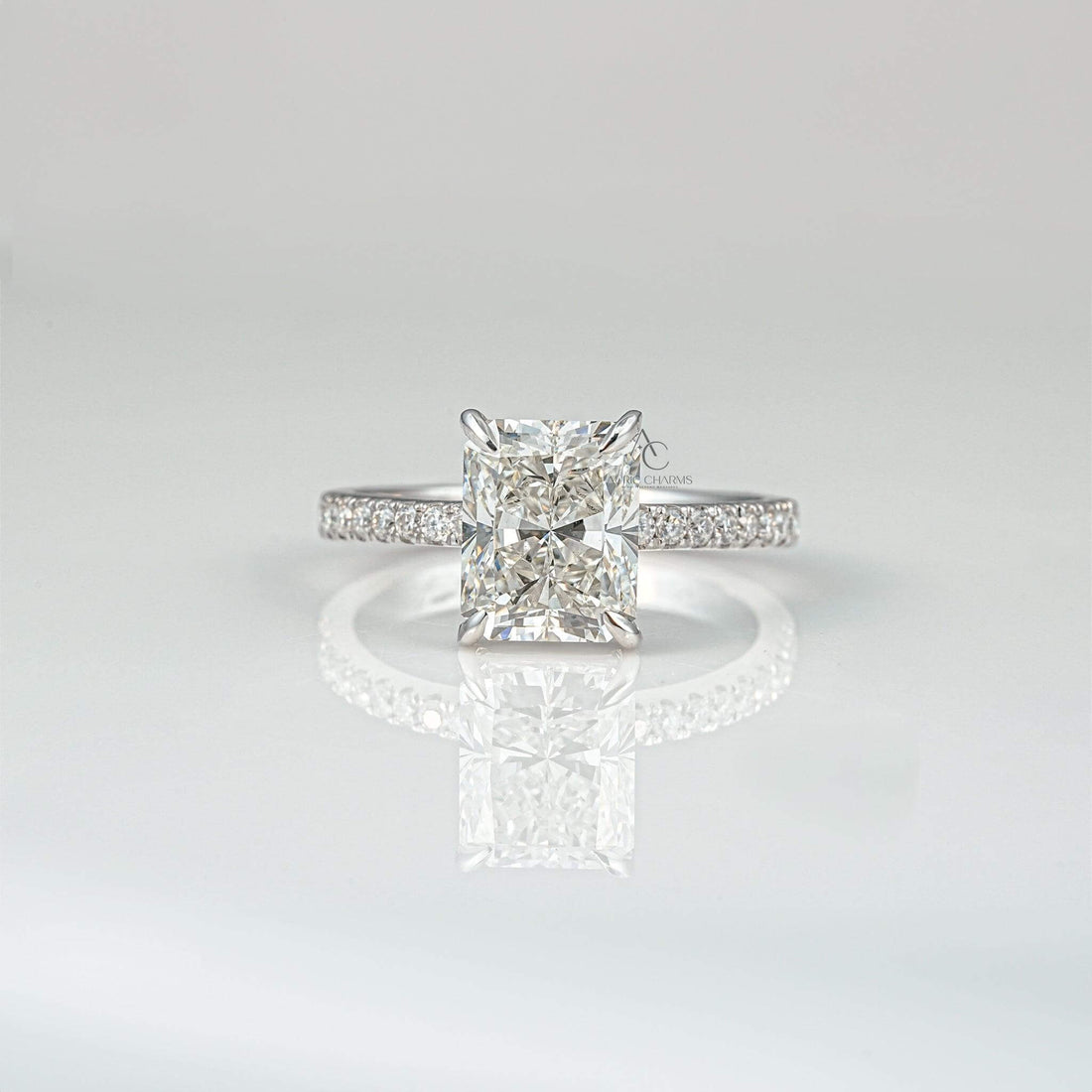 Radiant-cut diamond ring with a sleek band on a reflective surface.