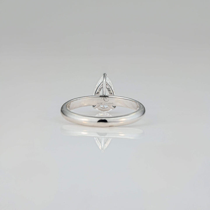 Rear view of a pear-cut lab-grown diamond solitaire ring highlighting the unique setting and attention to detail, set against a minimalist reflective background