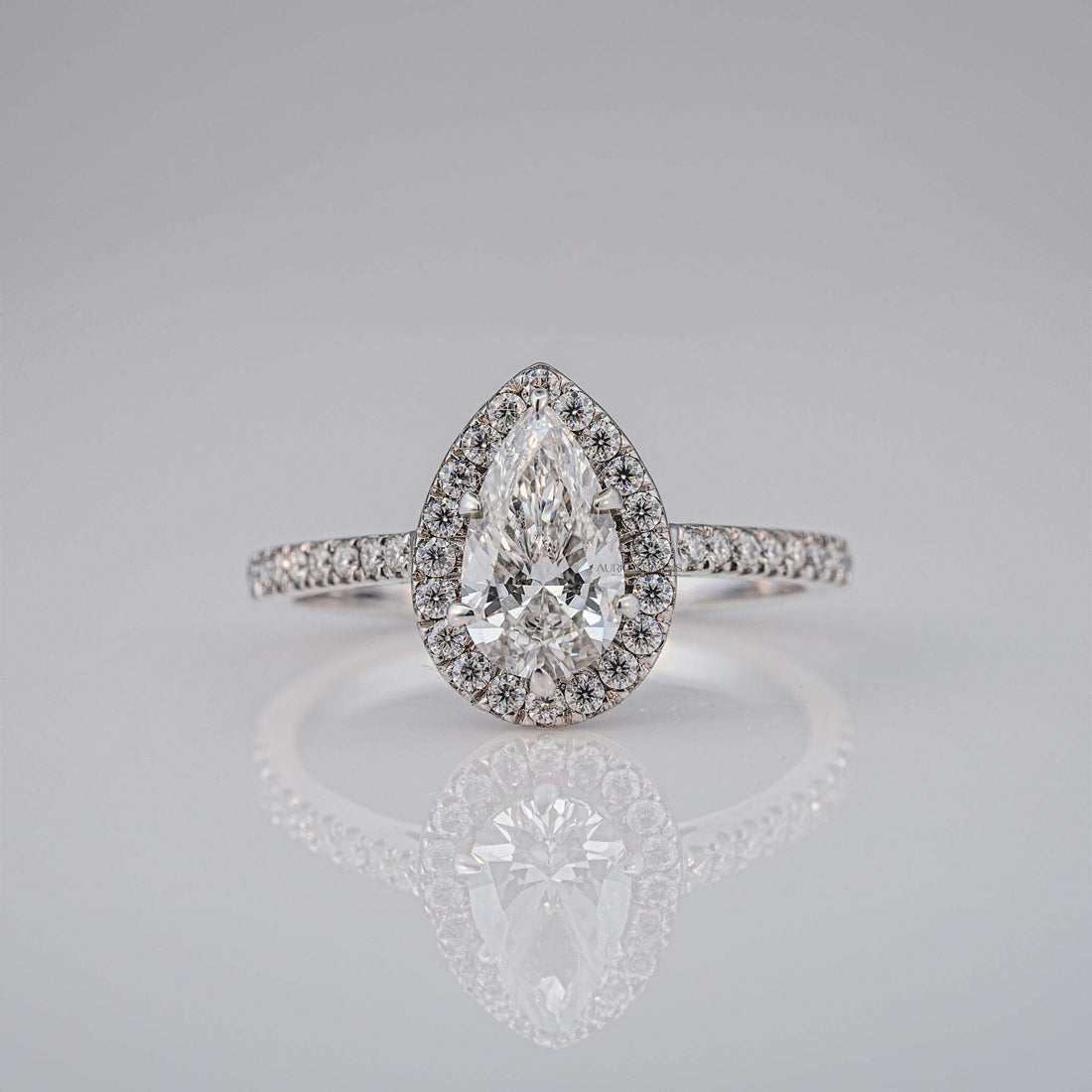 Front view of a pear-cut diamond ring with halo design and sparkling diamonds.