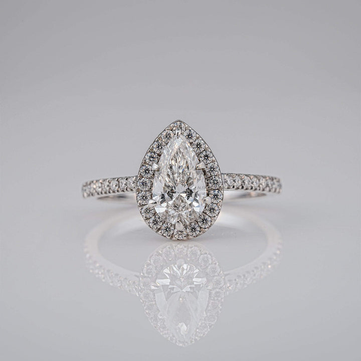 Front view of a pear-cut diamond ring with halo design and sparkling diamonds.
