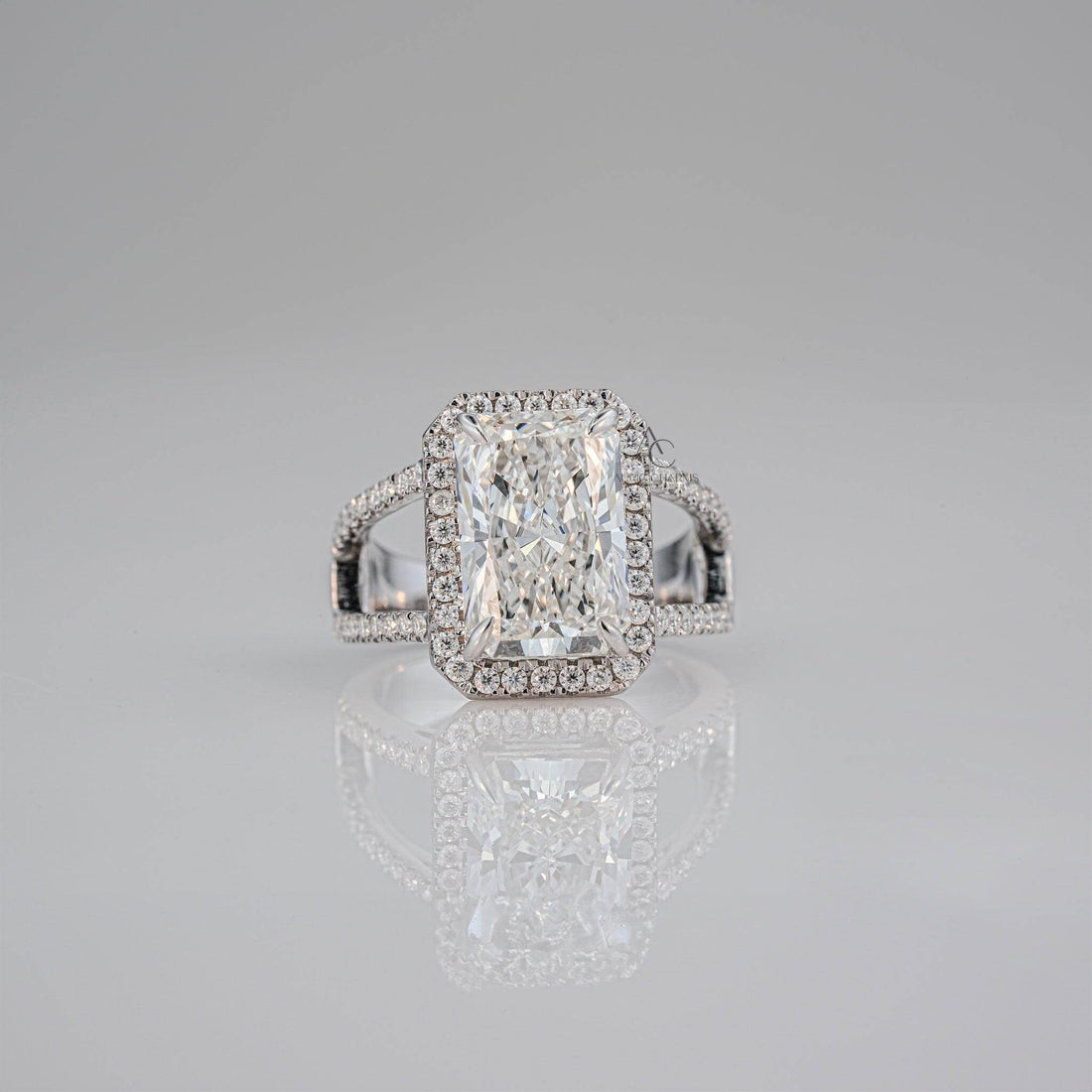 Radiant-cut diamond ring with a halo setting and intricate side detailing.
