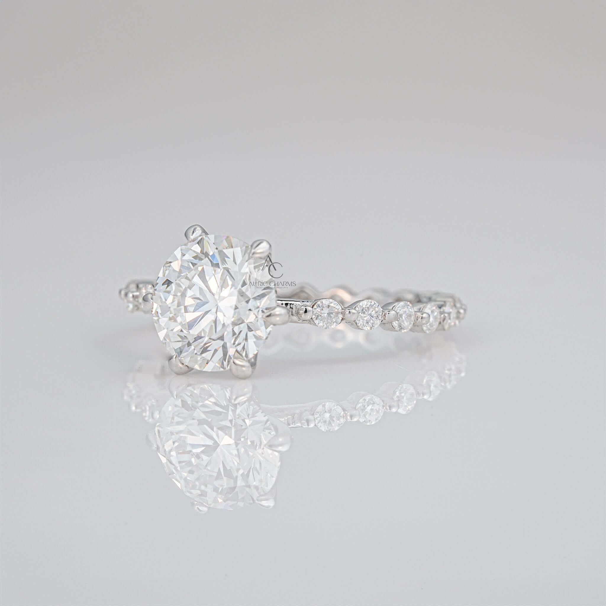 Side view of round-cut diamond ring with pave setting on sleek silver band.