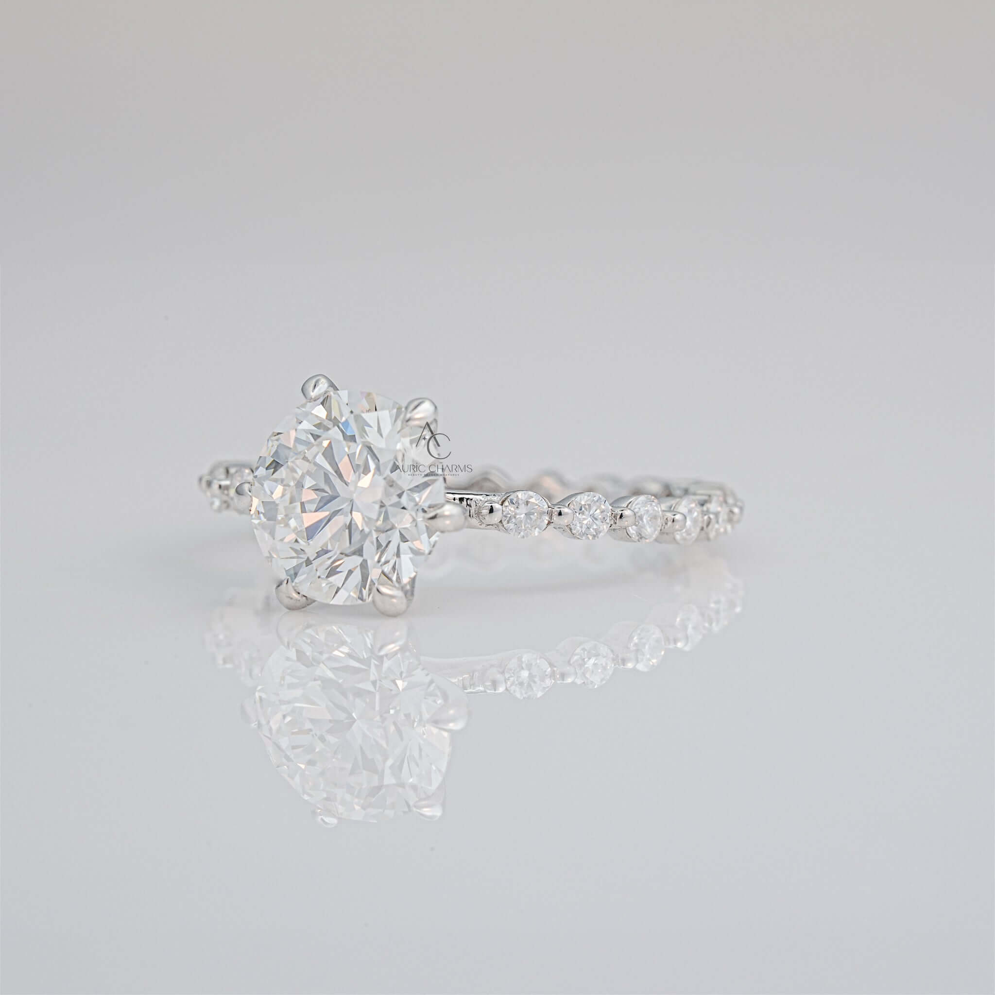 Close-up of diamond ring with round solitaire and delicate pave band.