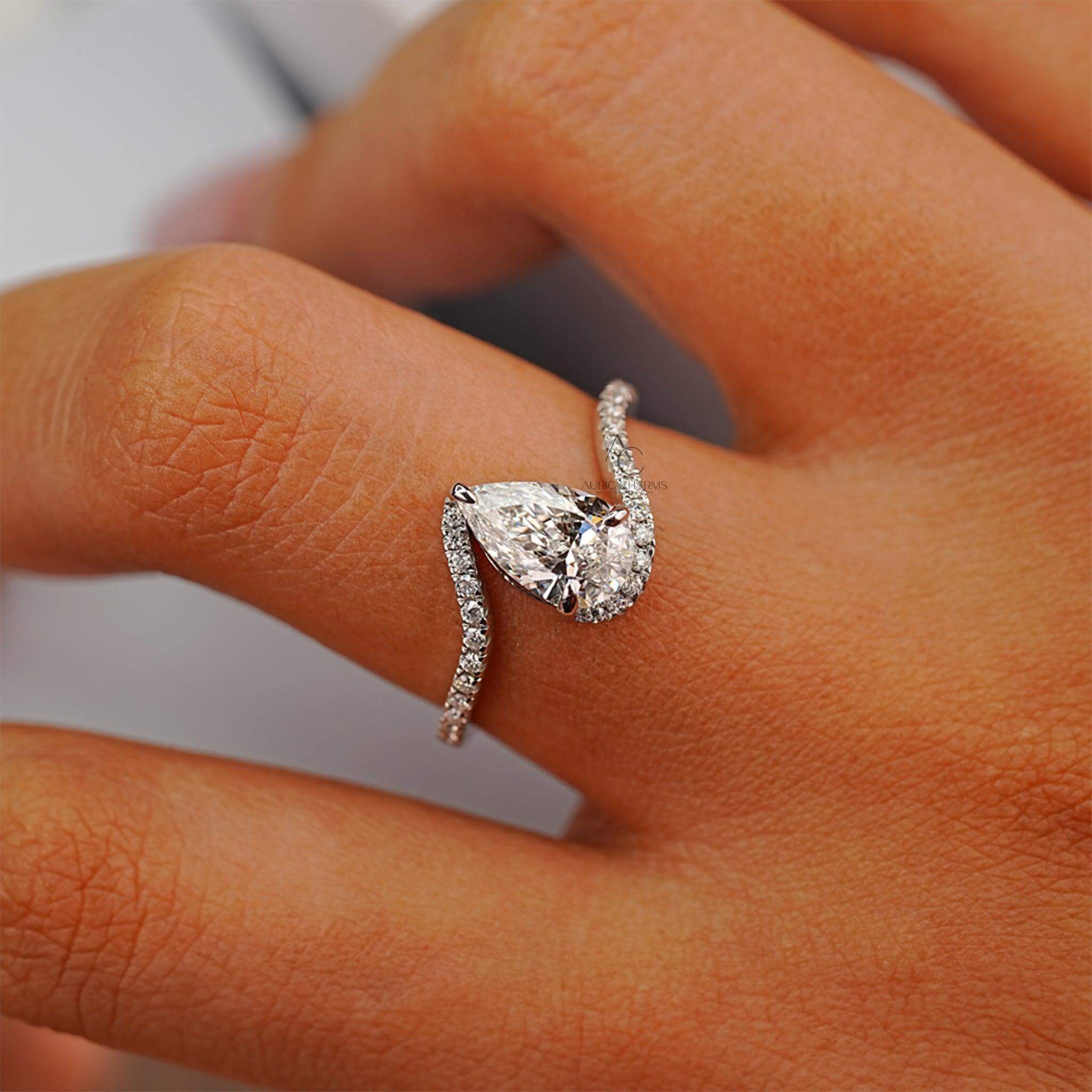 Pear-shaped diamond ring with a swirl pavé band worn on a hand, emphasizing elegance.