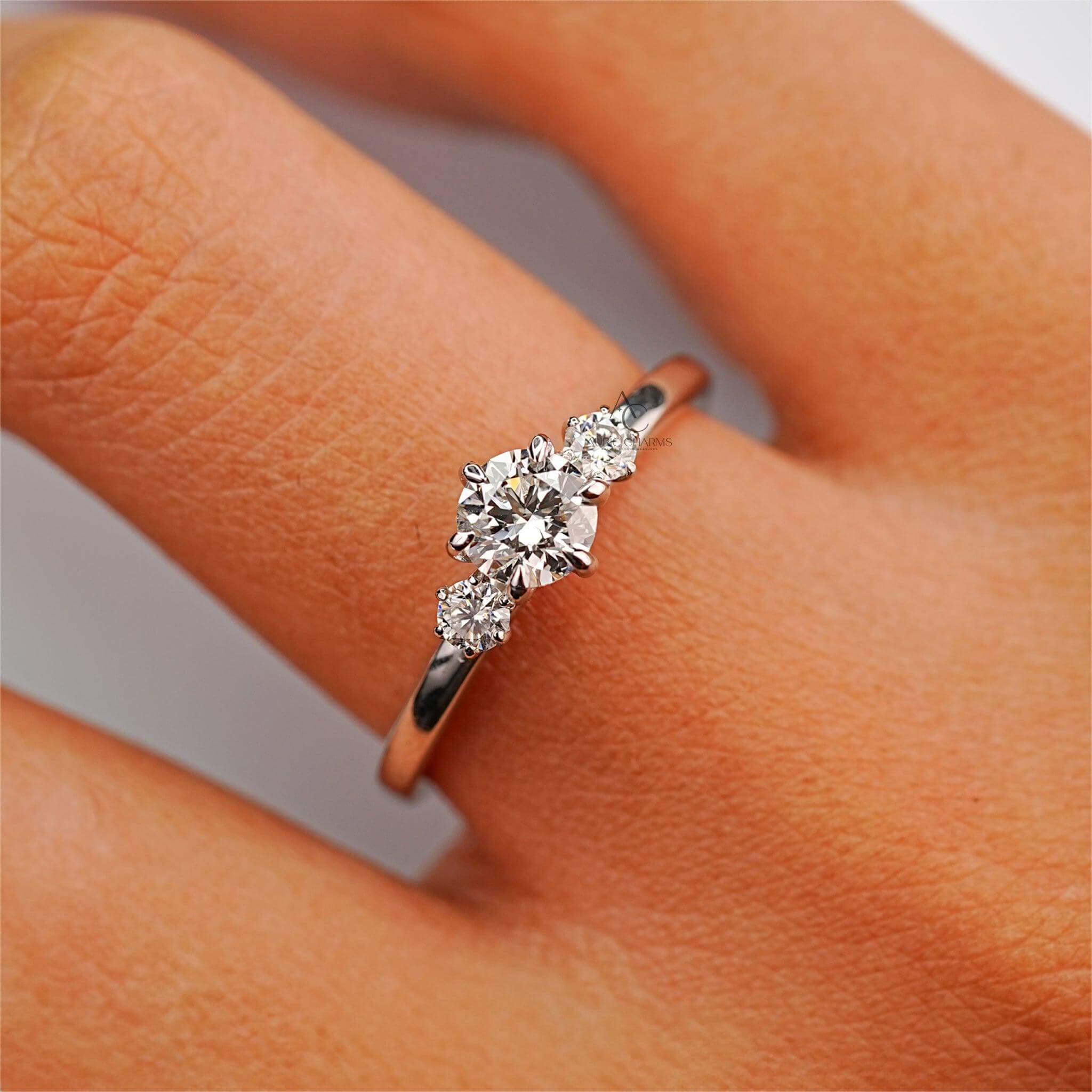 Stylish three-stone round diamond engagement ring worn on finger.