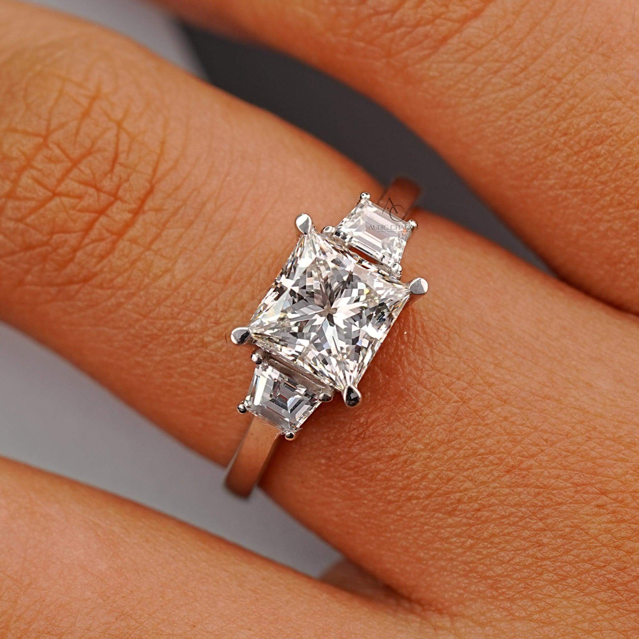 Elegant princess-cut diamond engagement ring with baguette accents worn on a finger.
