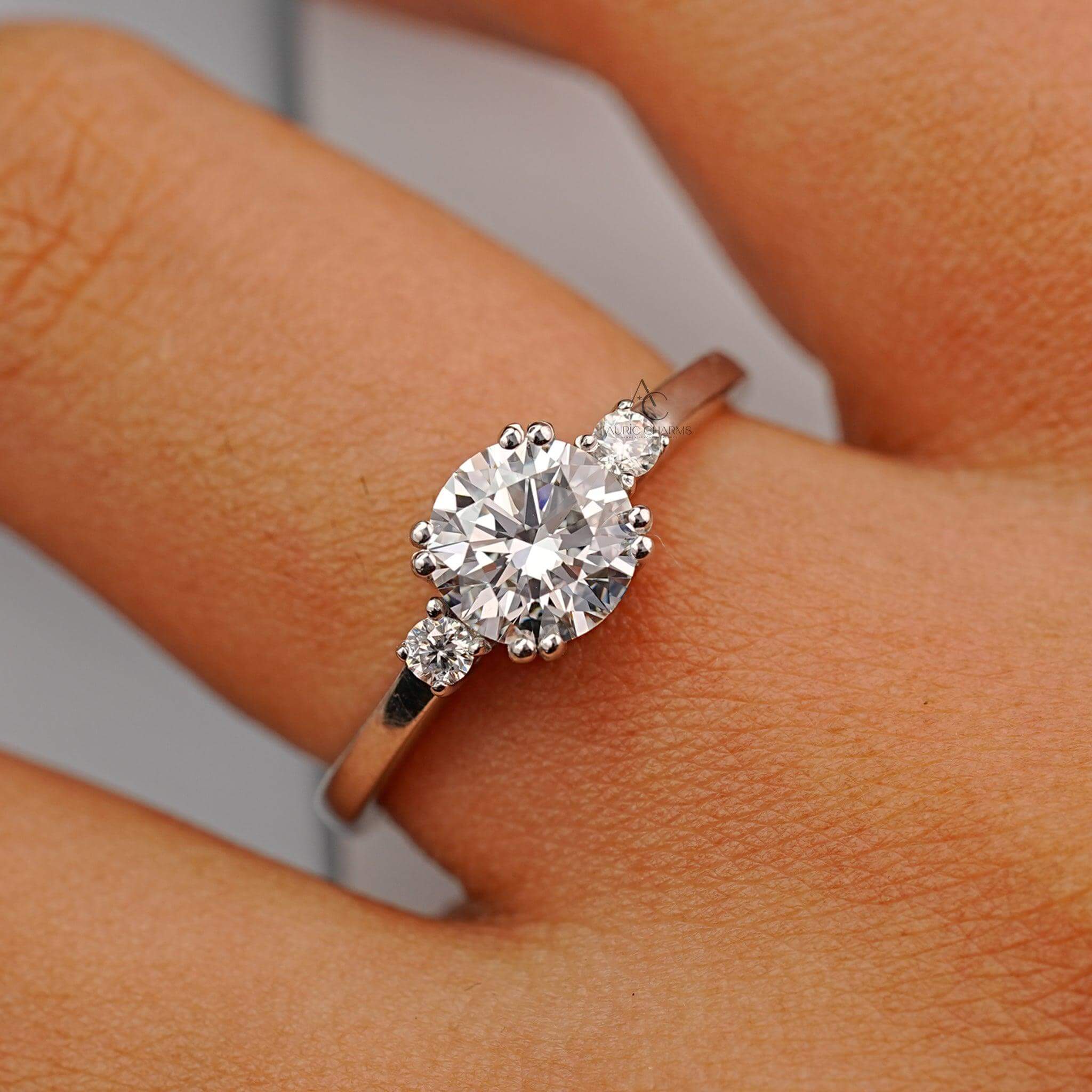 A round-cut diamond engagement ring with a three-stone design, elegantly worn on a hand for a timeless look.