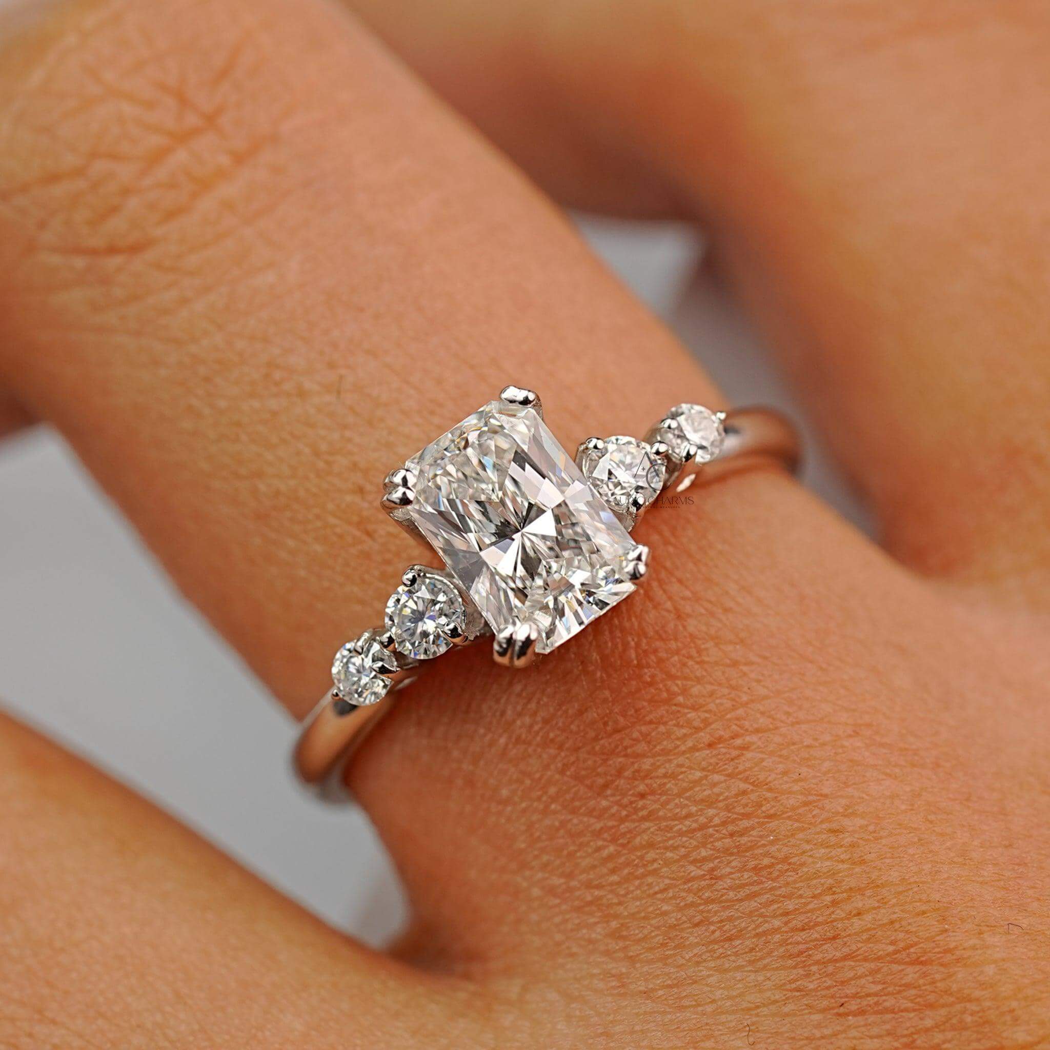 Radiant-cut diamond ring with side stones displayed on a hand for a classy look.