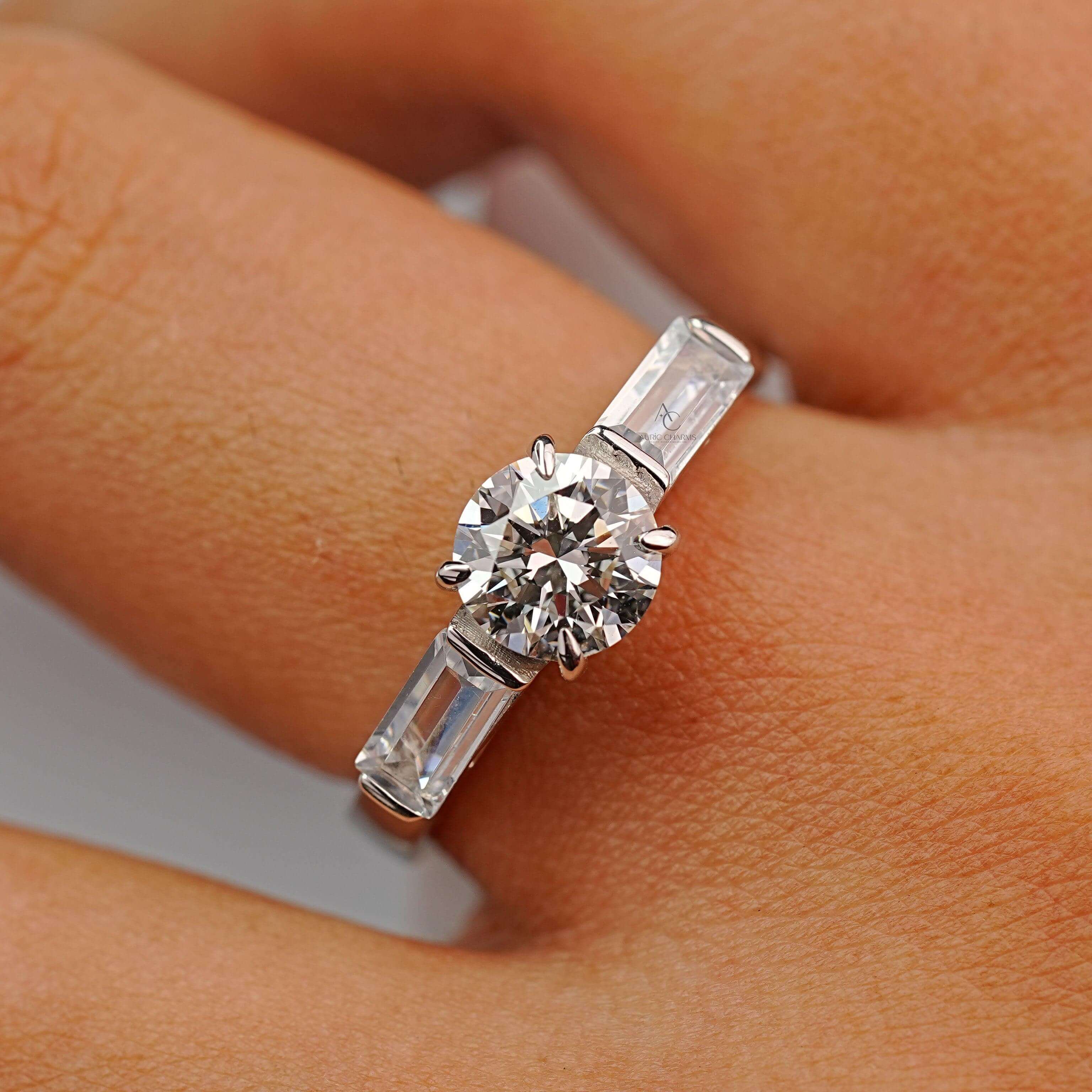 Close-up of a round diamond engagement ring with baguette side stones on a hand, illustrating luxurious simplicity.