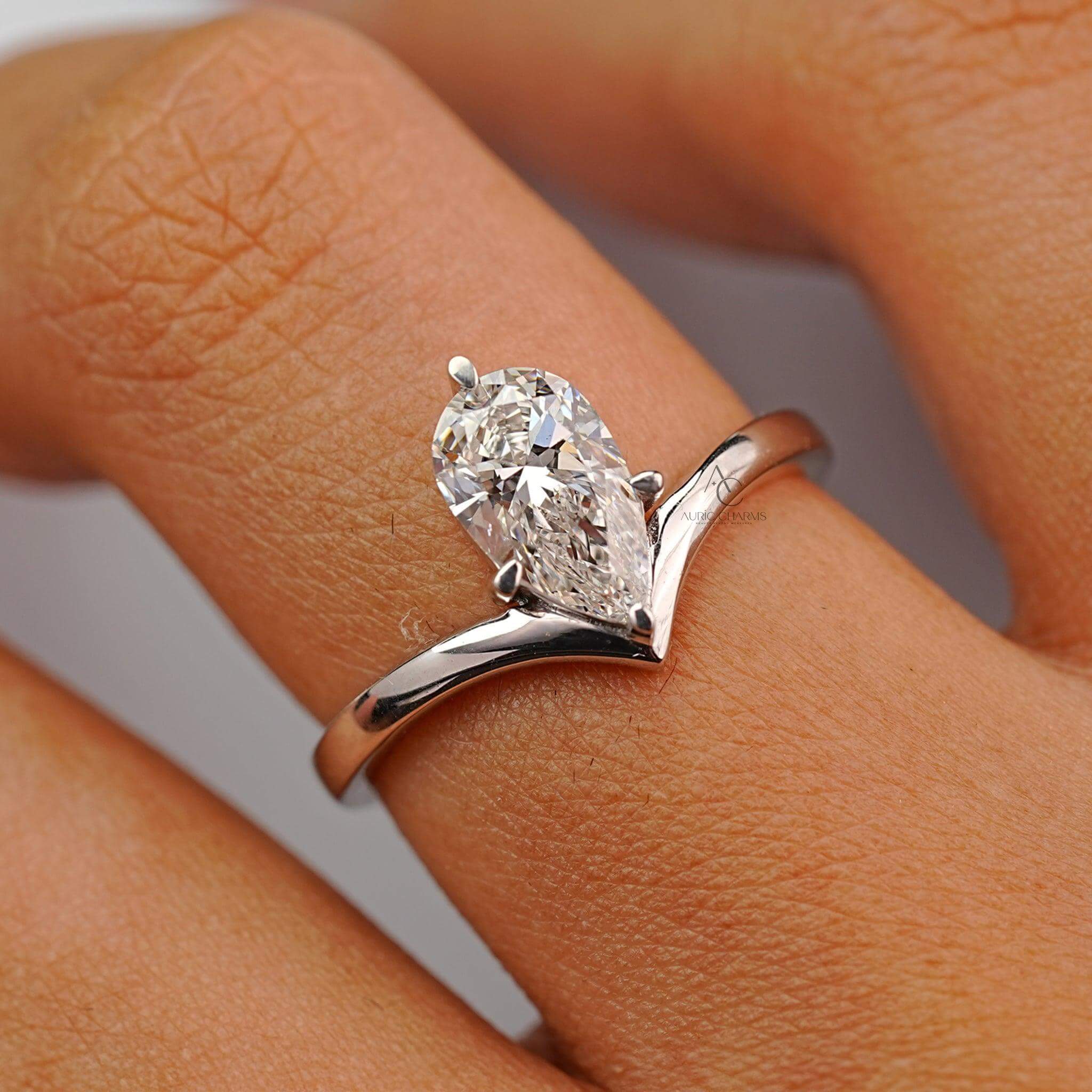 Close-up of a pear-cut diamond engagement ring worn on a finger, emphasizing its sparkle and modern design.