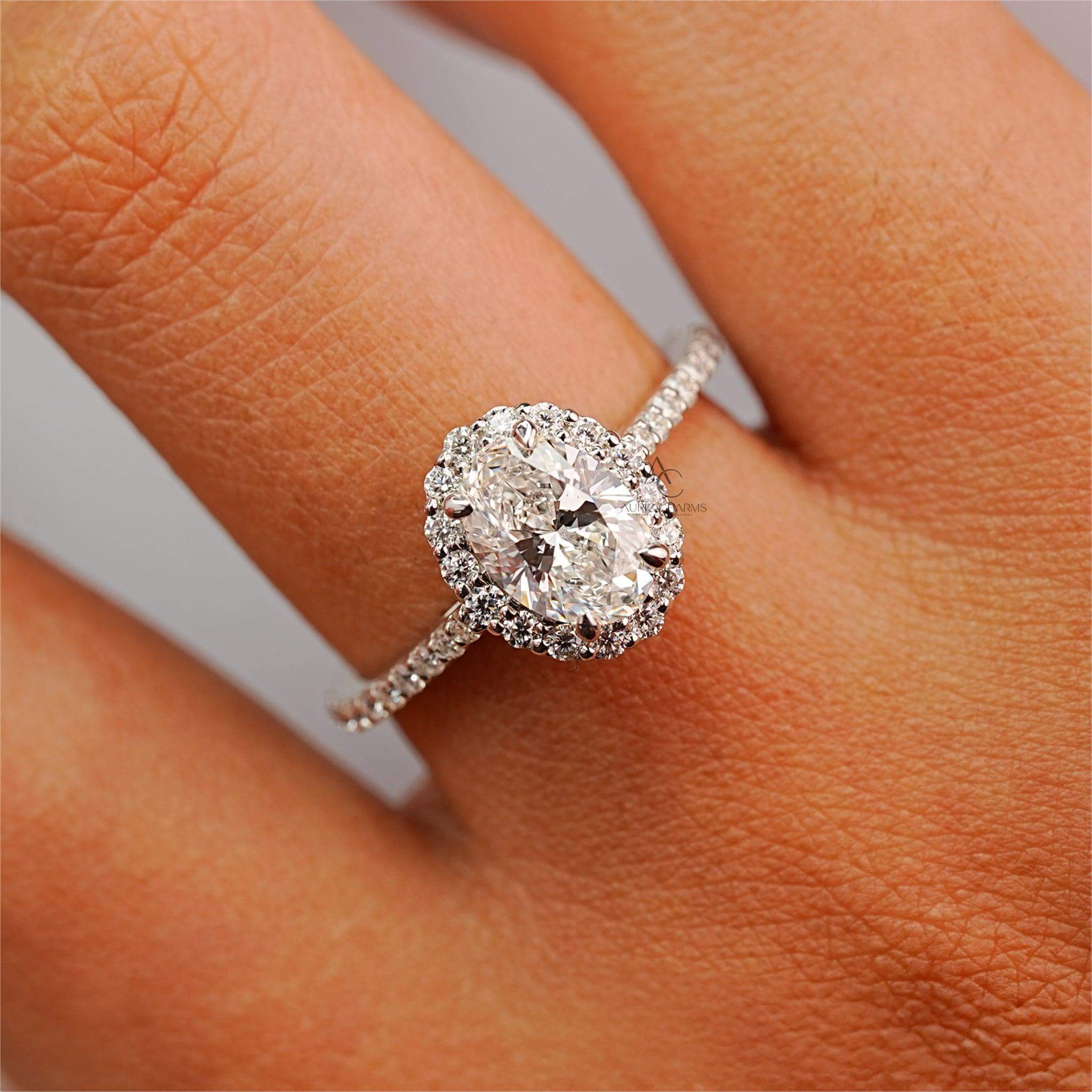 Oval-cut diamond halo ring worn on a hand, showcasing sparkle and elegance.