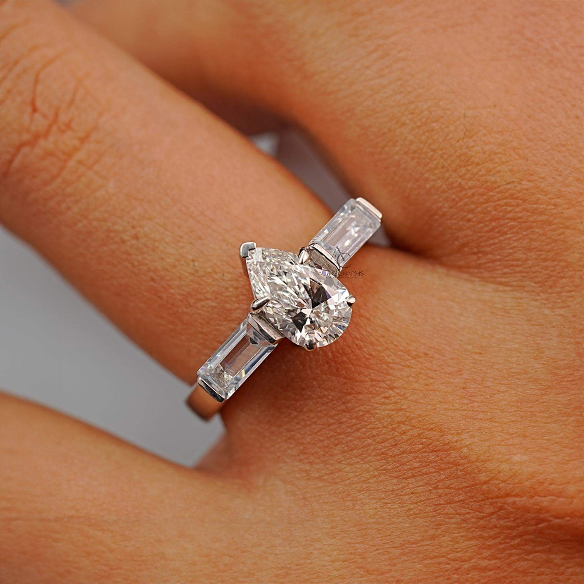 Pear-cut diamond ring with baguette side stones worn on a hand, showcasing luxury.