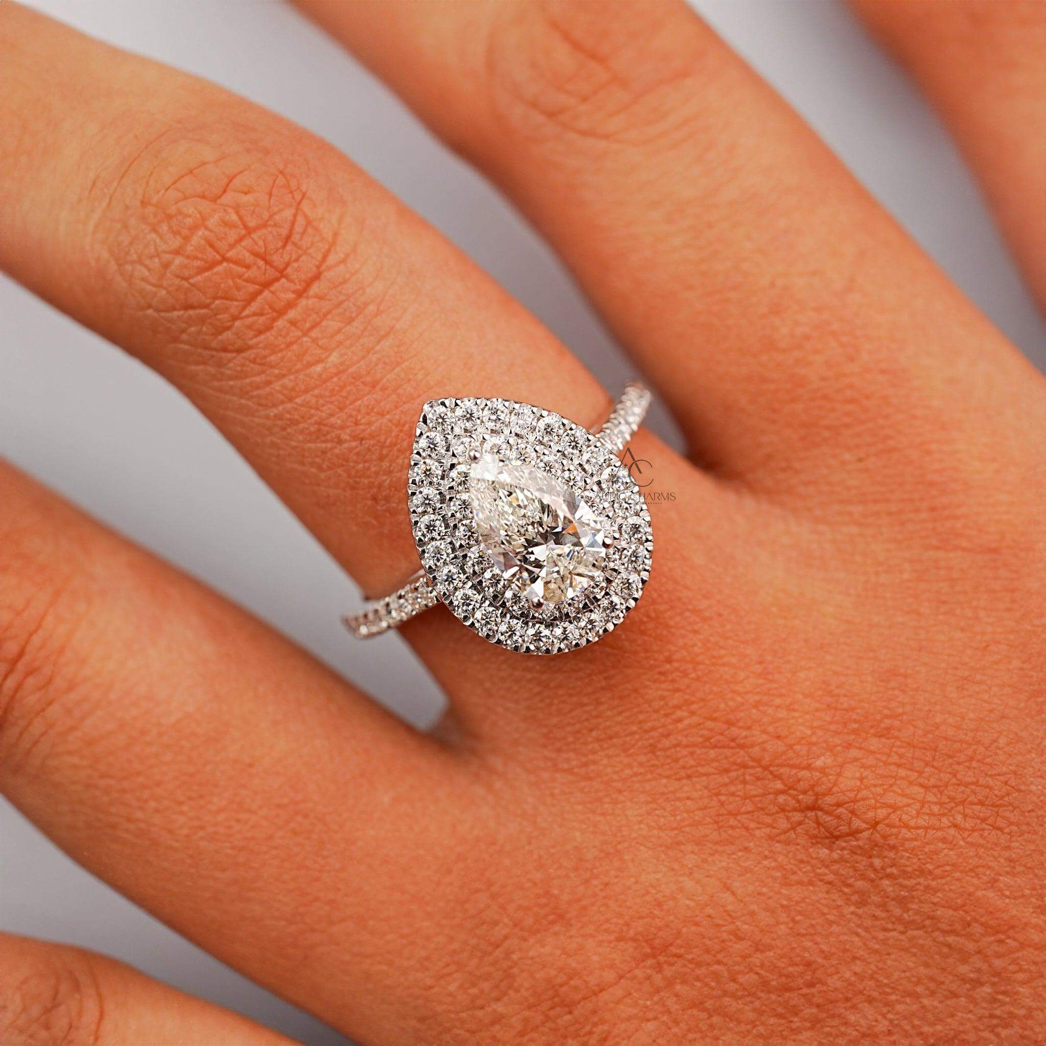 Pear-shaped diamond ring with a double halo worn on a hand, showcasing luxury.